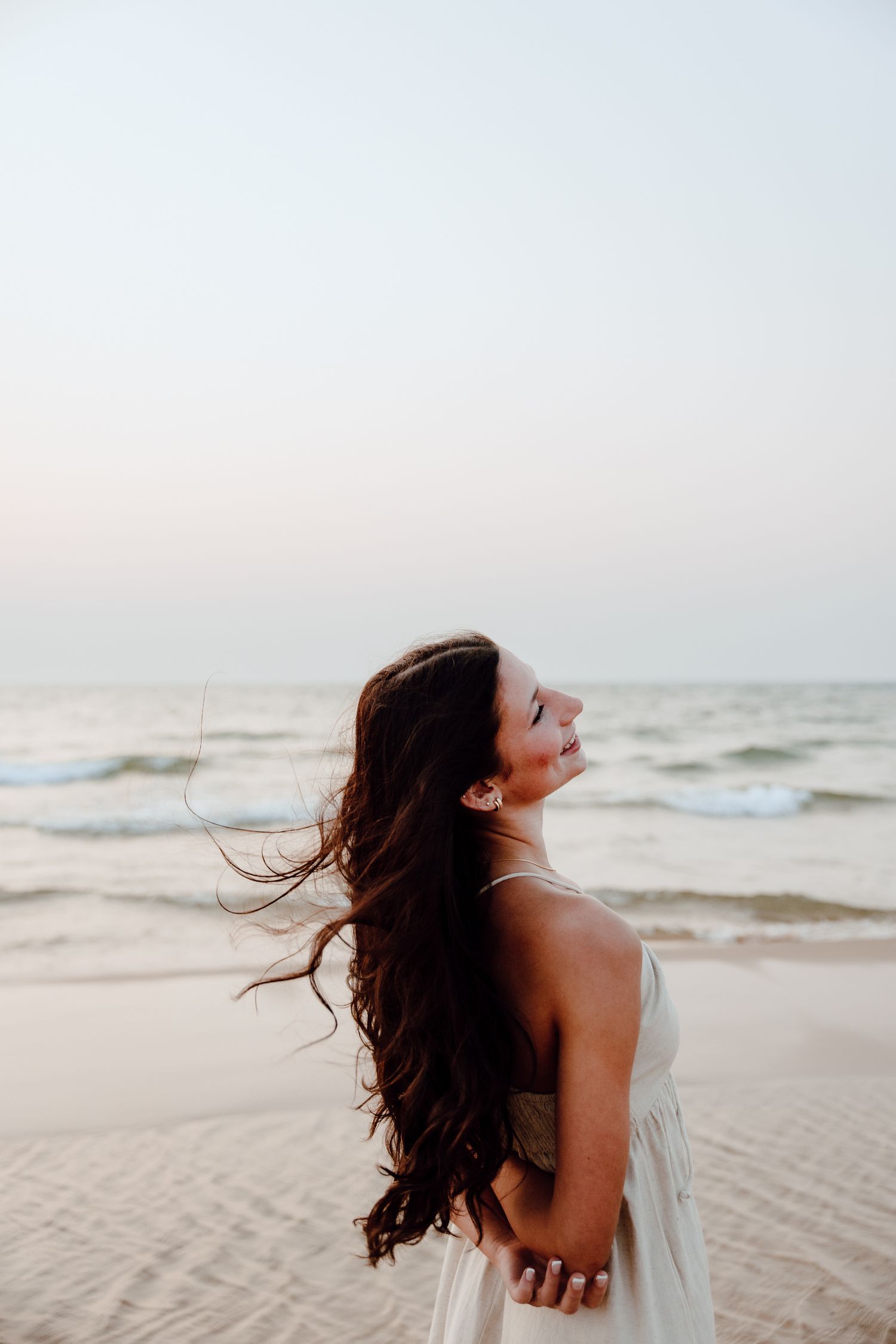 Candid beach portraits with wind-swept hair against ocean backdrop.