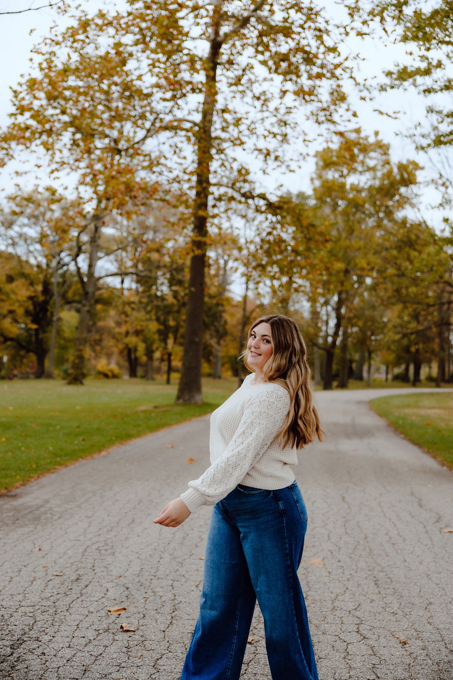Dancing and twirling on a gravel path surrounded by autumn trees.
