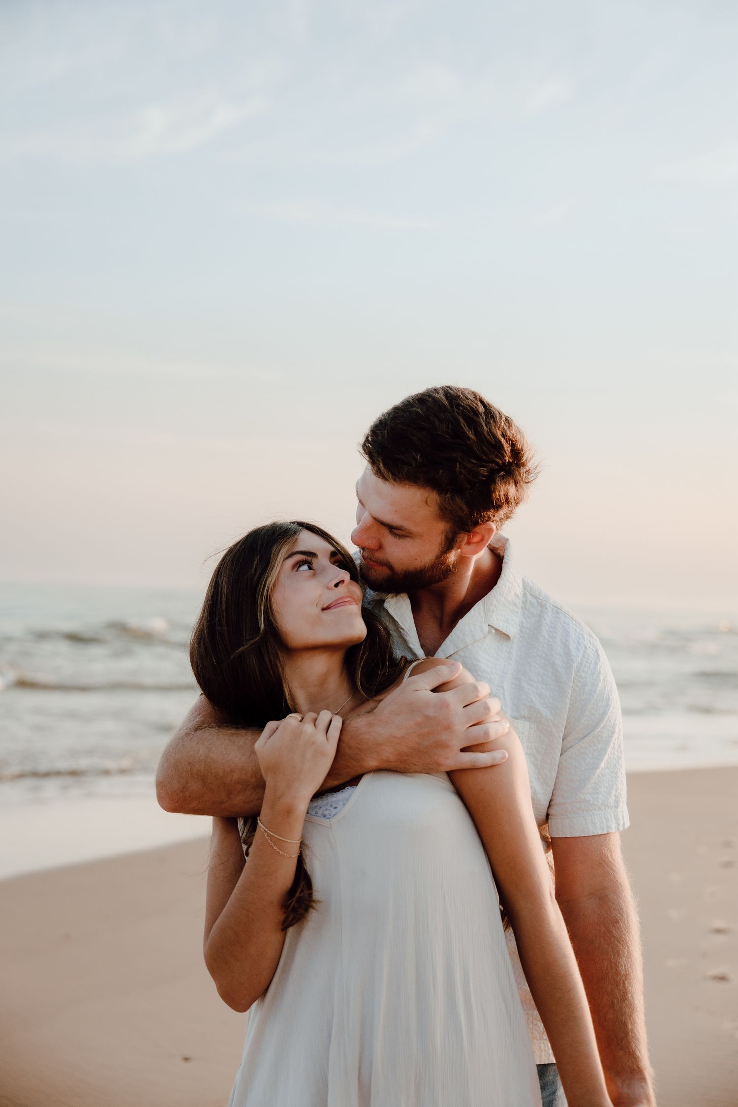 Intimate couple moment captured on a peaceful beach with soft sunset lighting.