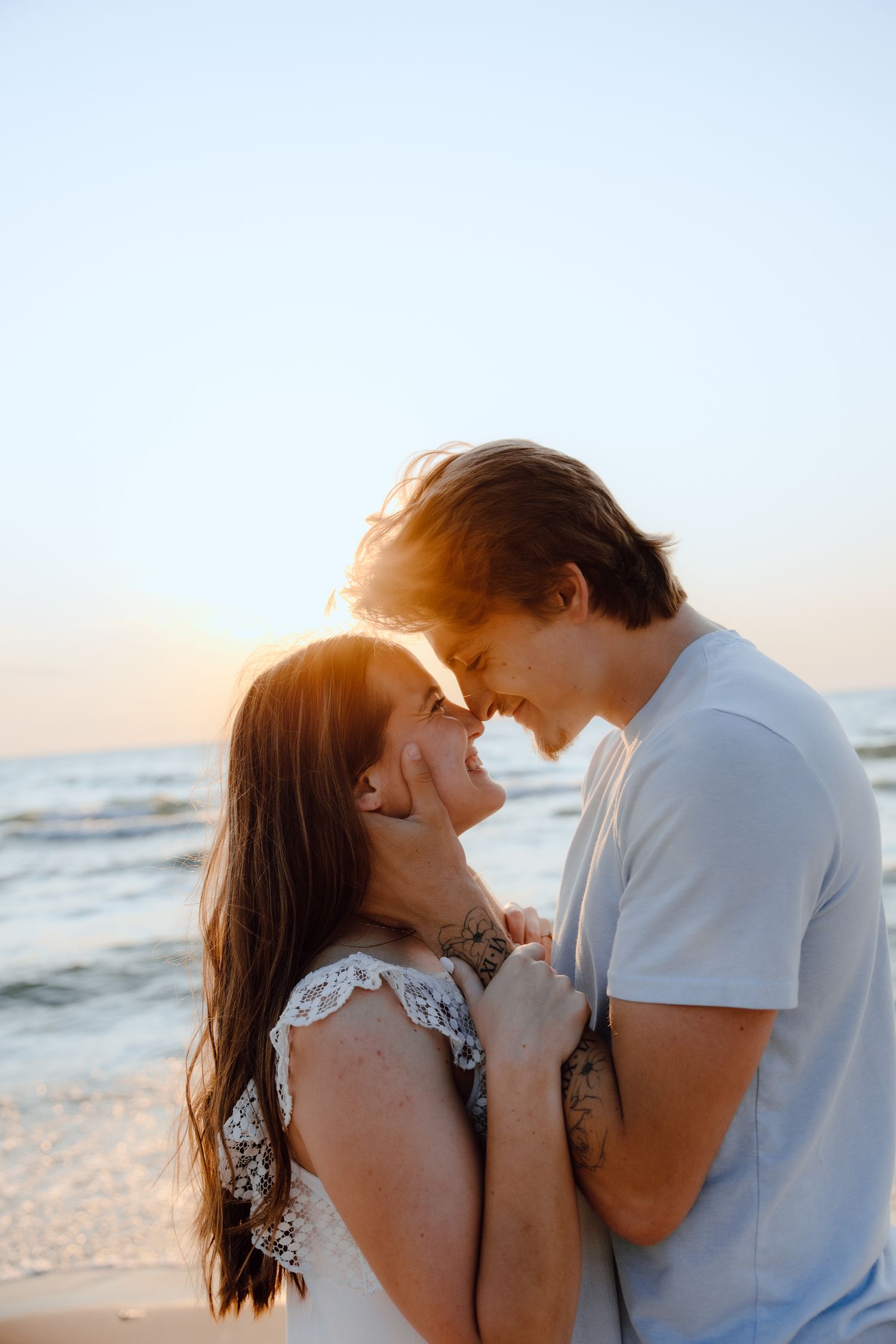A romantic sunset beach photoshoot with soft golden lighting.