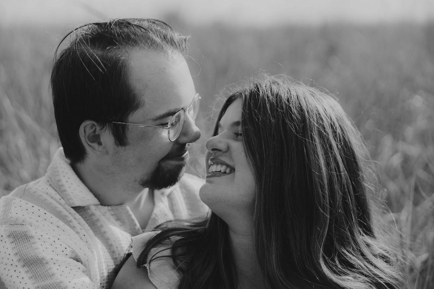 Intimate black and white portrait of a couple sharing a joyful moment outdoors.
