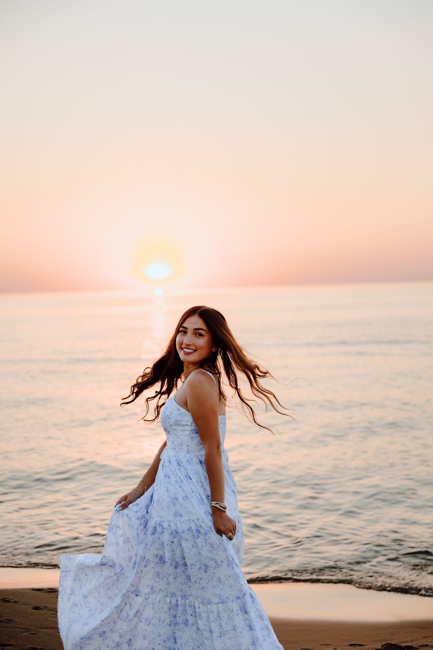 A flowy white sundress catches the breeze during a beach sunset photoshoot.