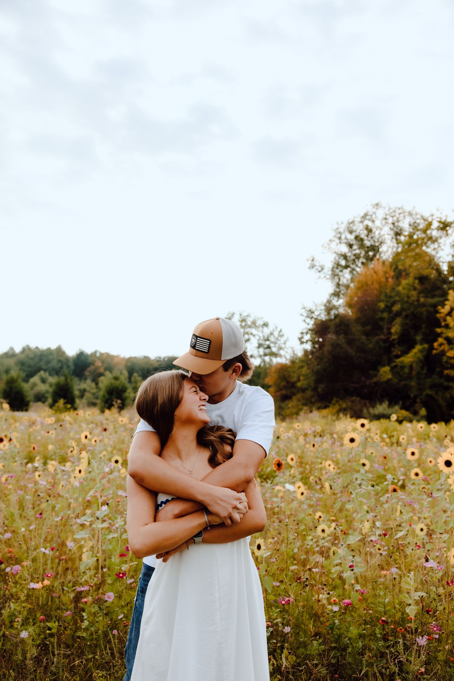 A couple embraces in a wildflower field during summer.