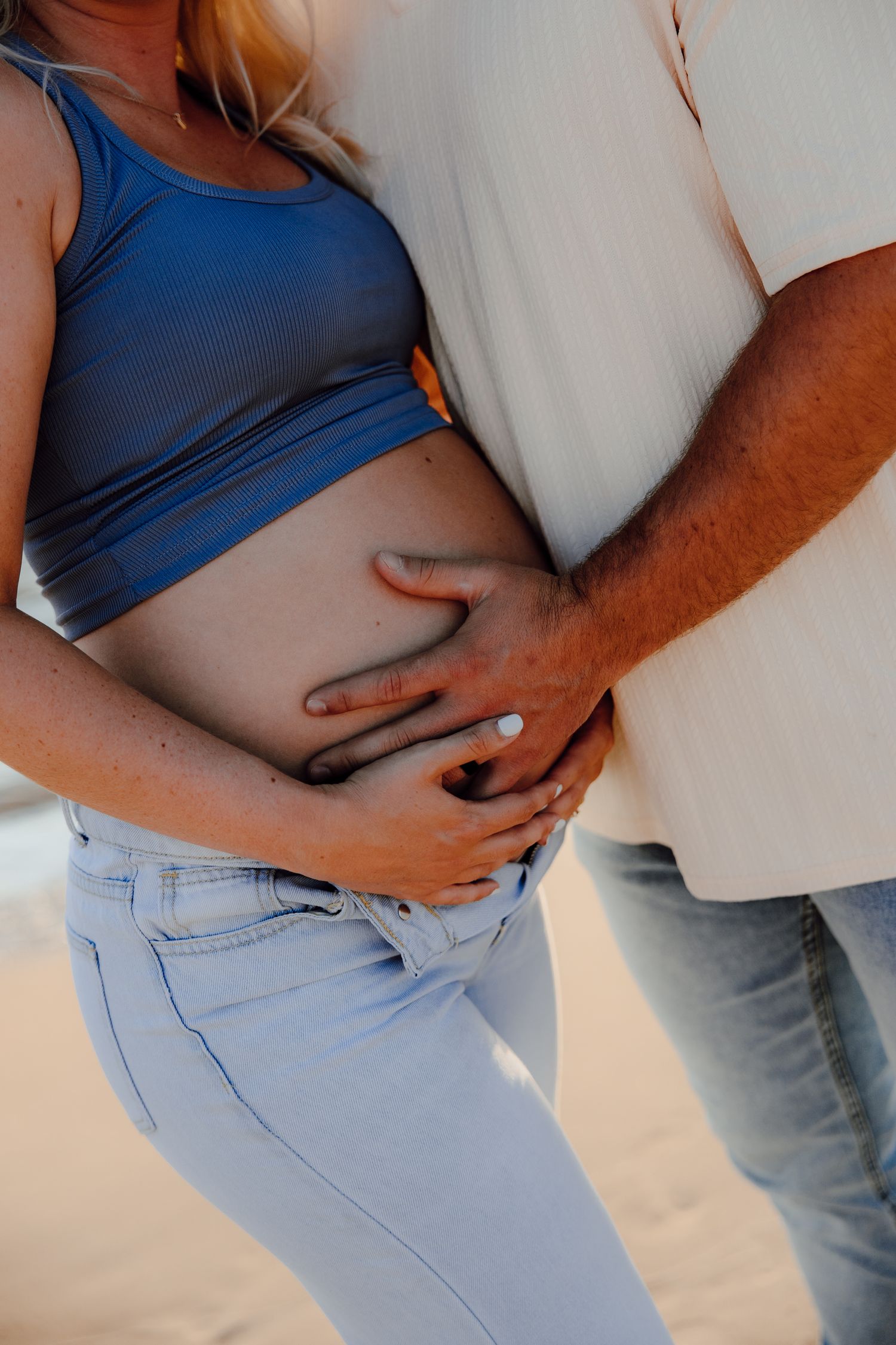Close-up shots of expecting couple's hands cradling baby bump.
