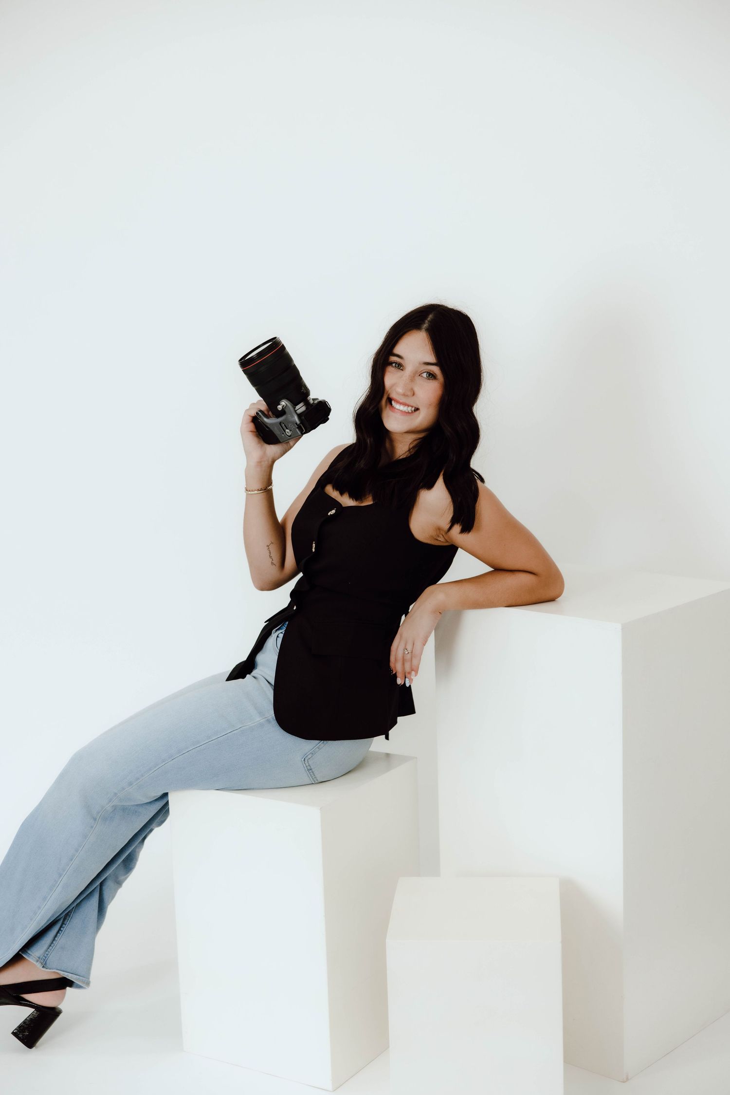 Photographer poses with camera on white geometric steps in creative positions.
