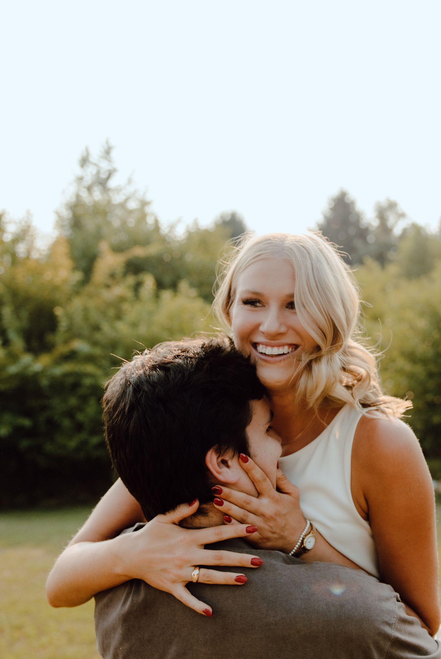 Romantic couple sharing playful kisses in a grassy outdoor setting during golden hour.