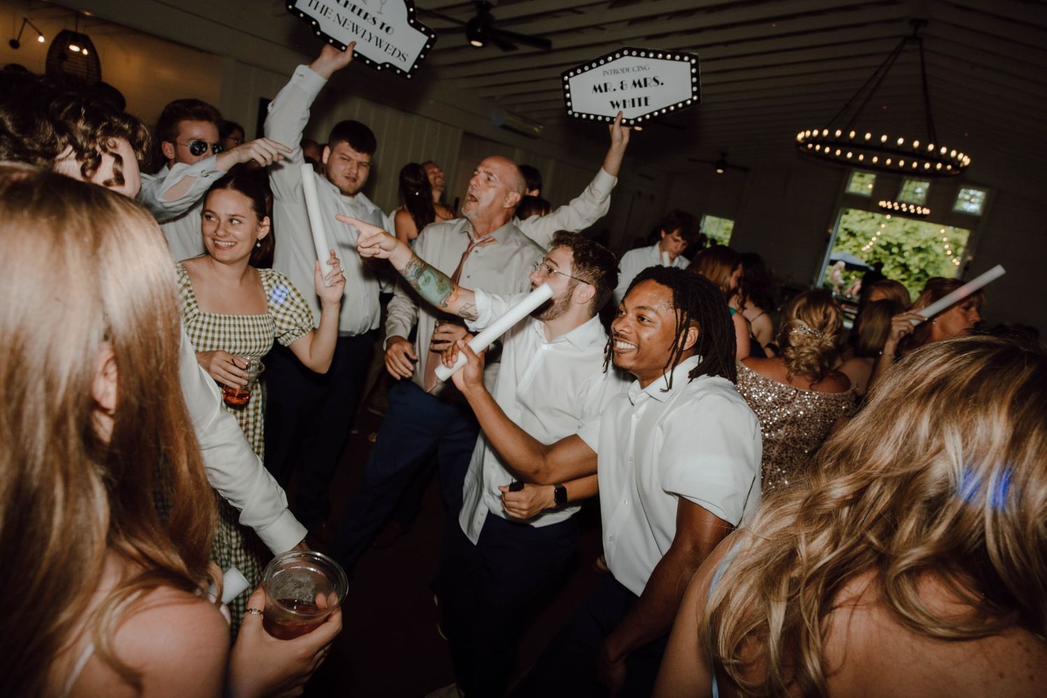 Guests dancing and celebrating at a lively wedding reception party indoors with festive decorations.
