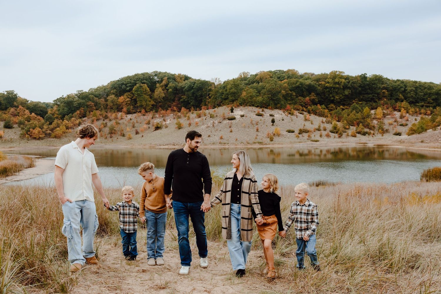 A group walks together along a scenic trail surrounded by autumn hills.