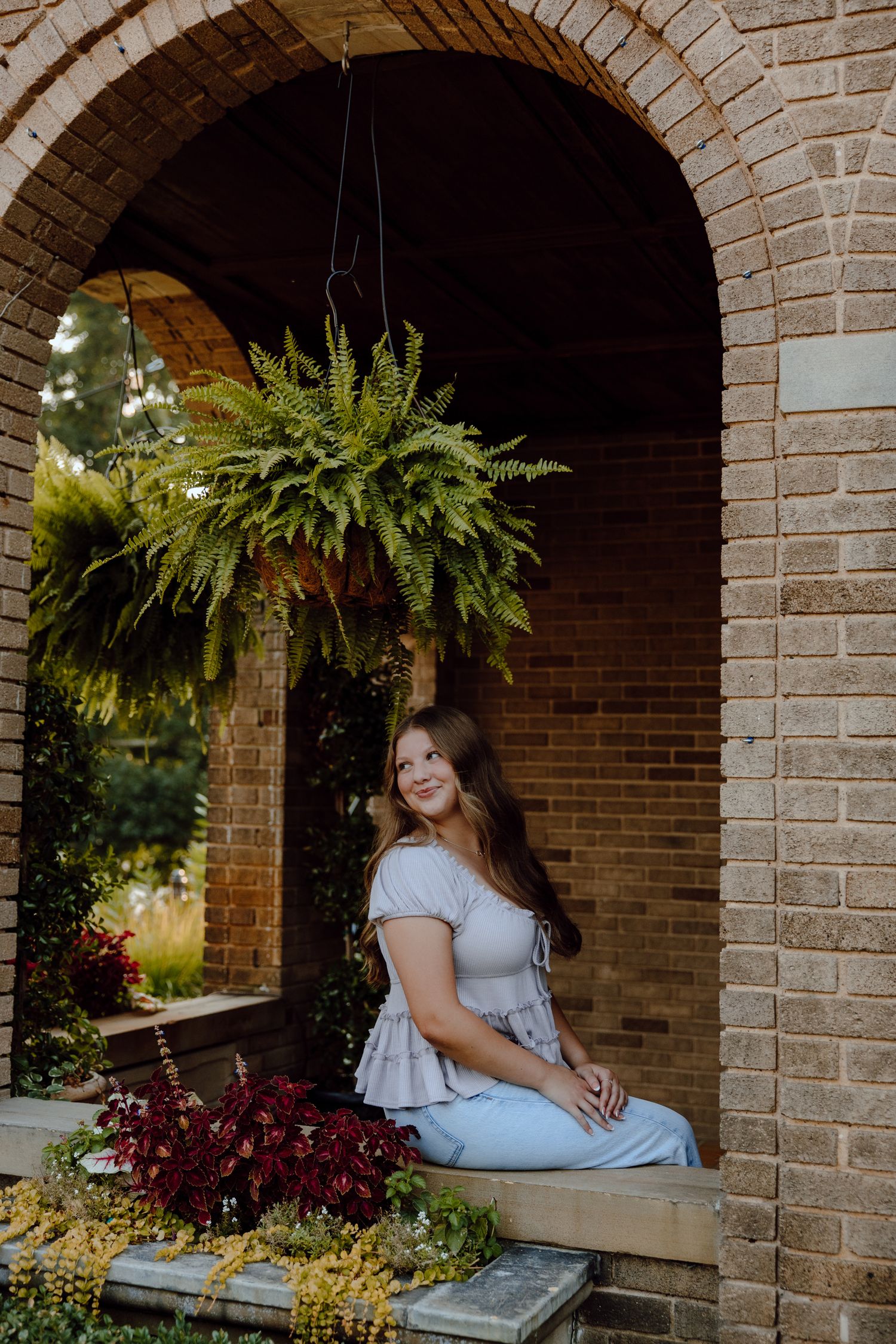 Portrait series under brick archways decorated with hanging ferns and plants.