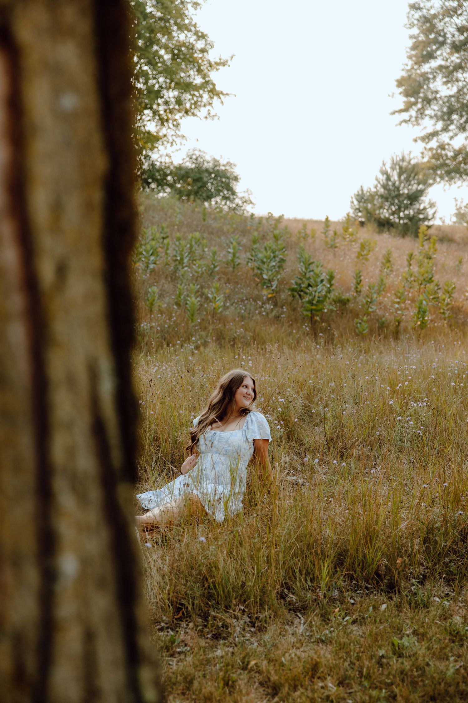 A dreamy scene of a person in white moving through tall grass at sunset.