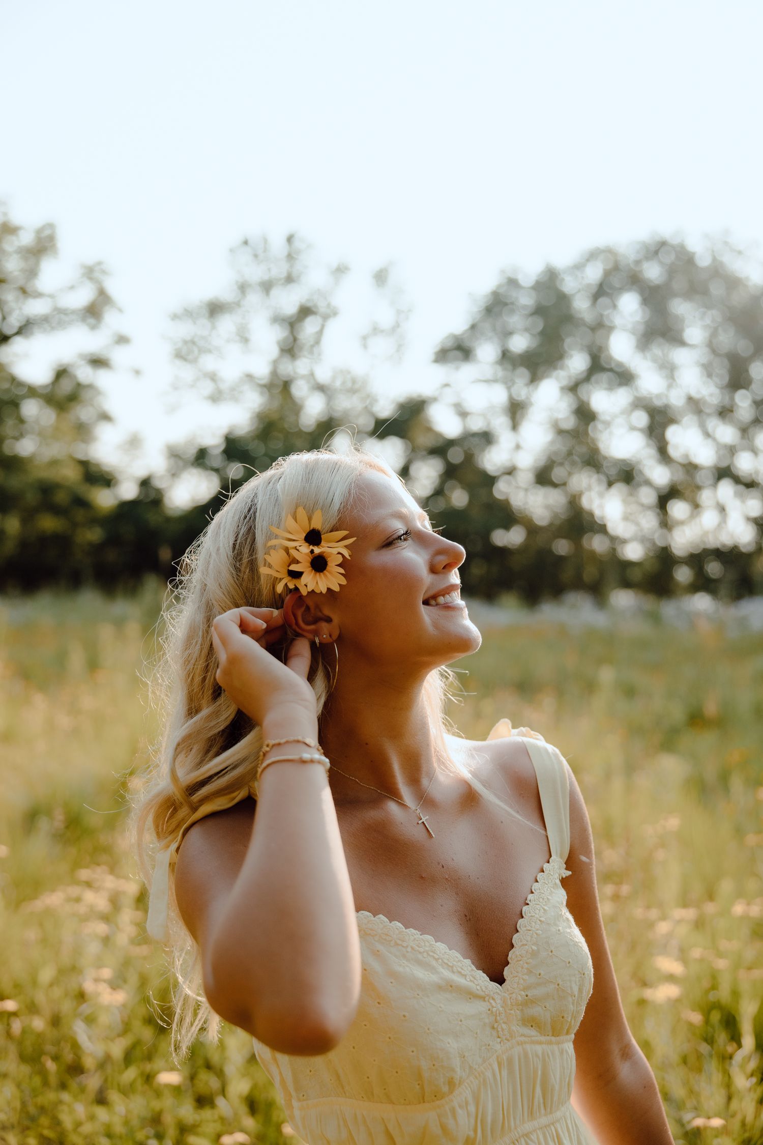A joyful summer portrait with a sunflower accent in a golden meadow at sunset.