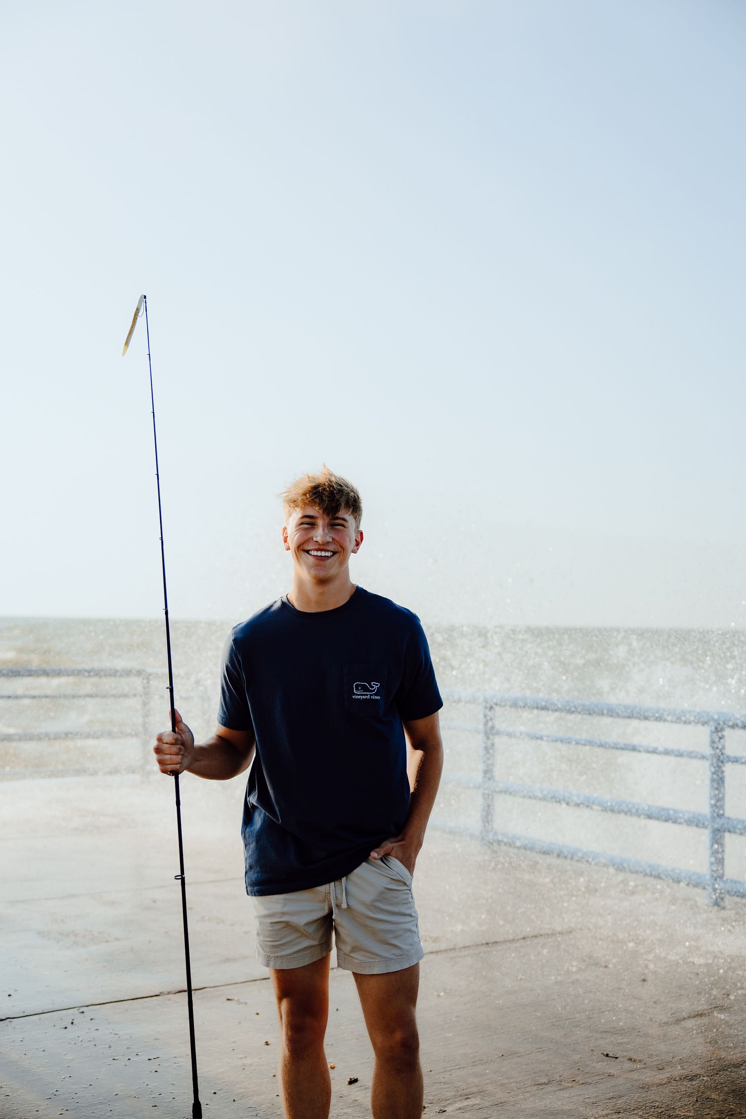 Person holding a fishing rod on a sunny beach.