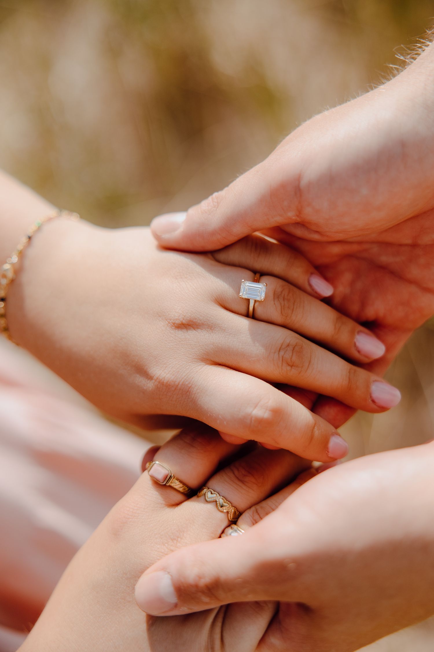 Close-up of hands with engagement rings showing a tender moment between a couple.