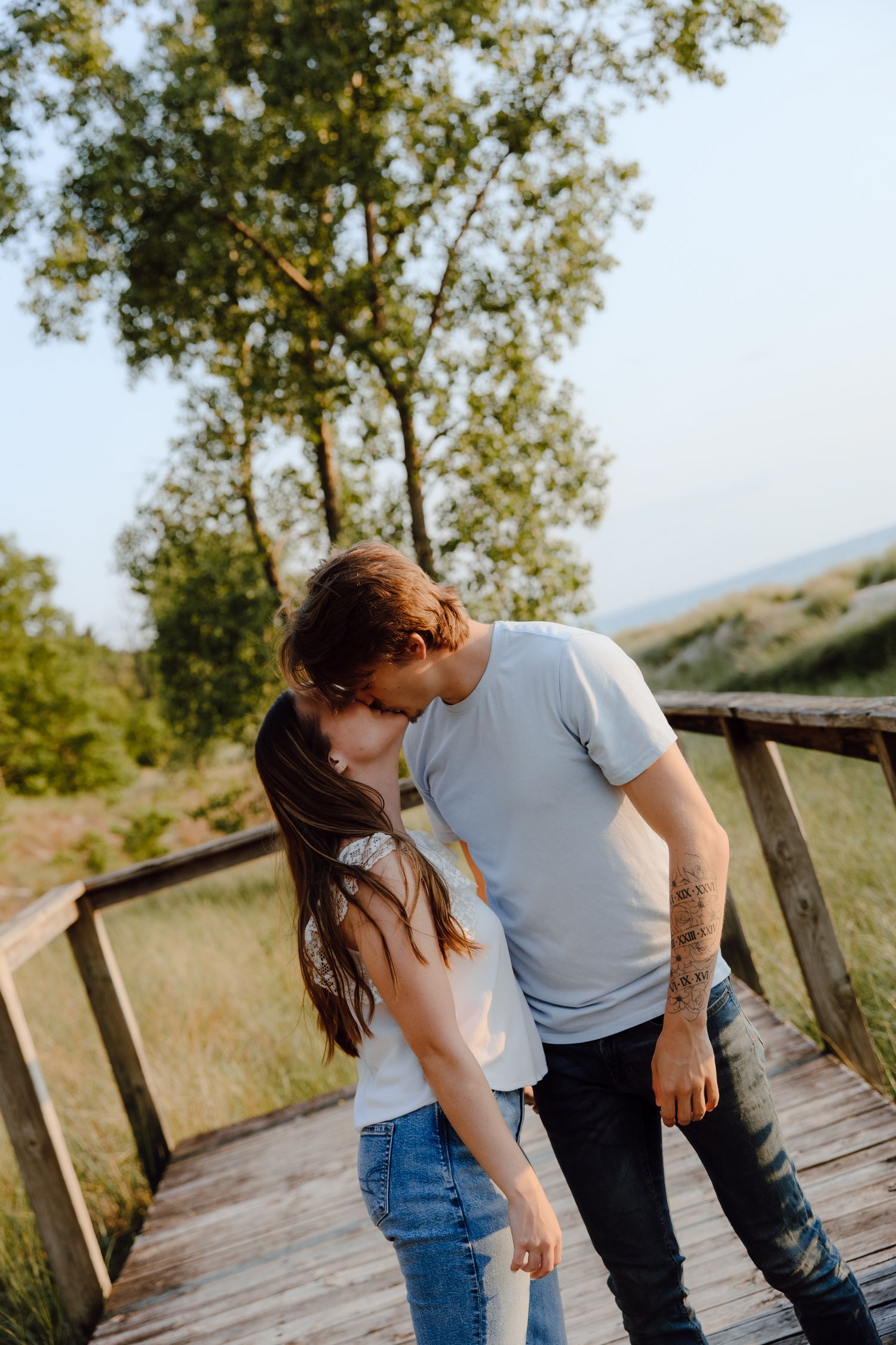 A couple sharing an intimate moment on a wooden walkway surrounded by nature.