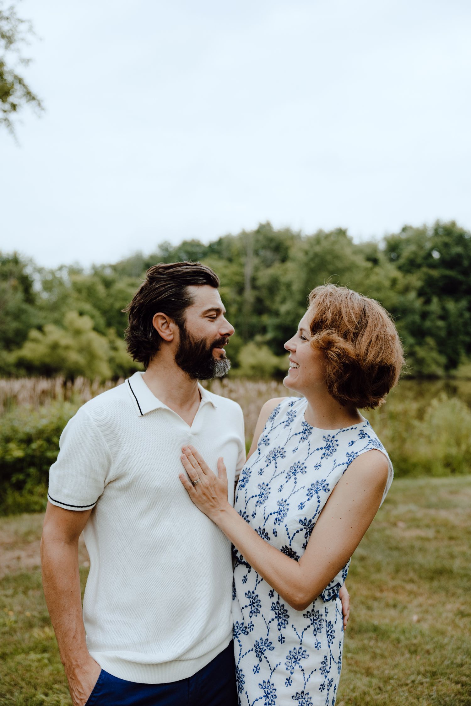 A couple shares a romantic moment outdoors wearing coordinating blue and white outfits.