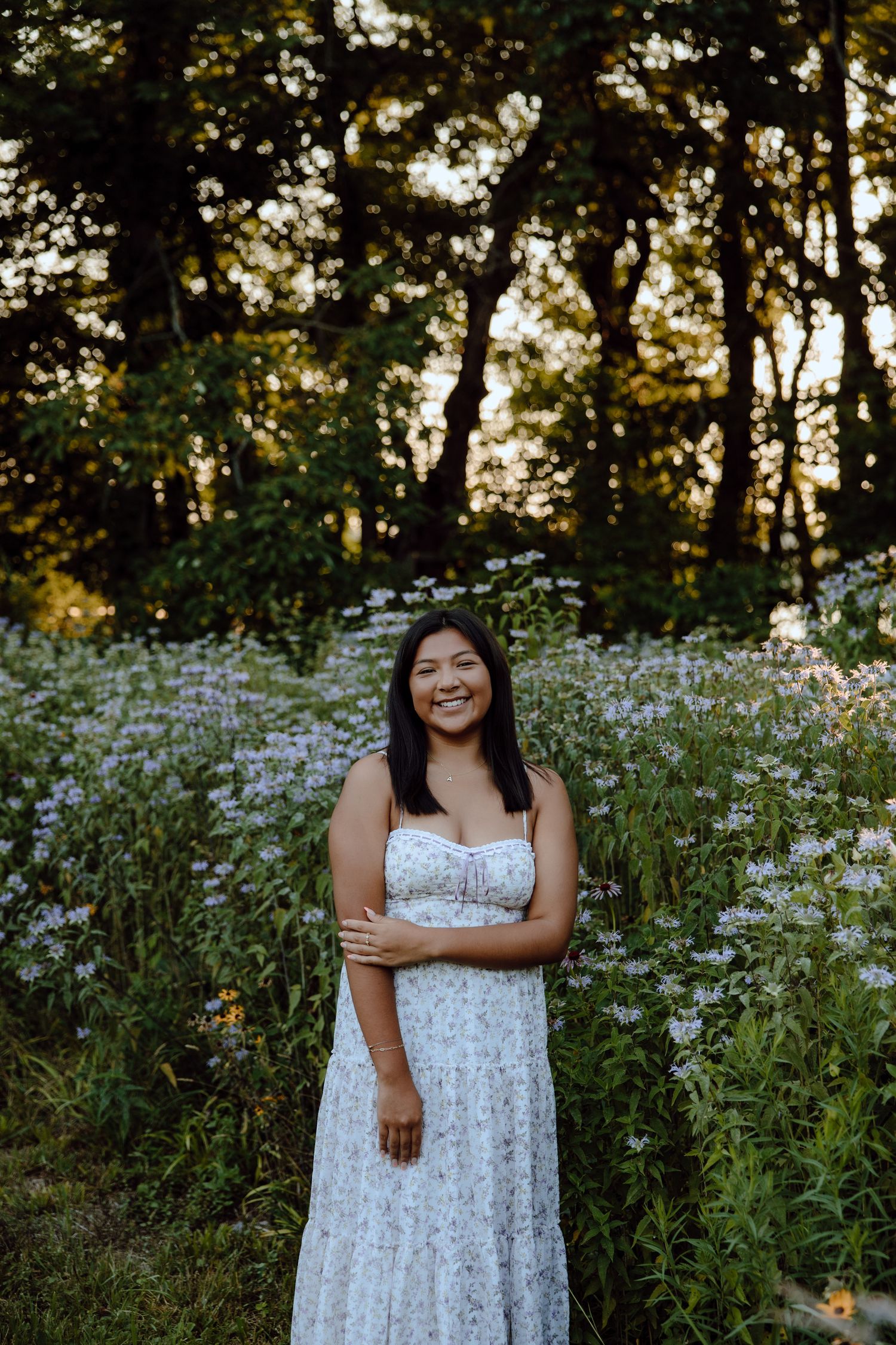 A white sundress photoshoot in a wildflower meadow during golden hour with daisies and natural scenery.