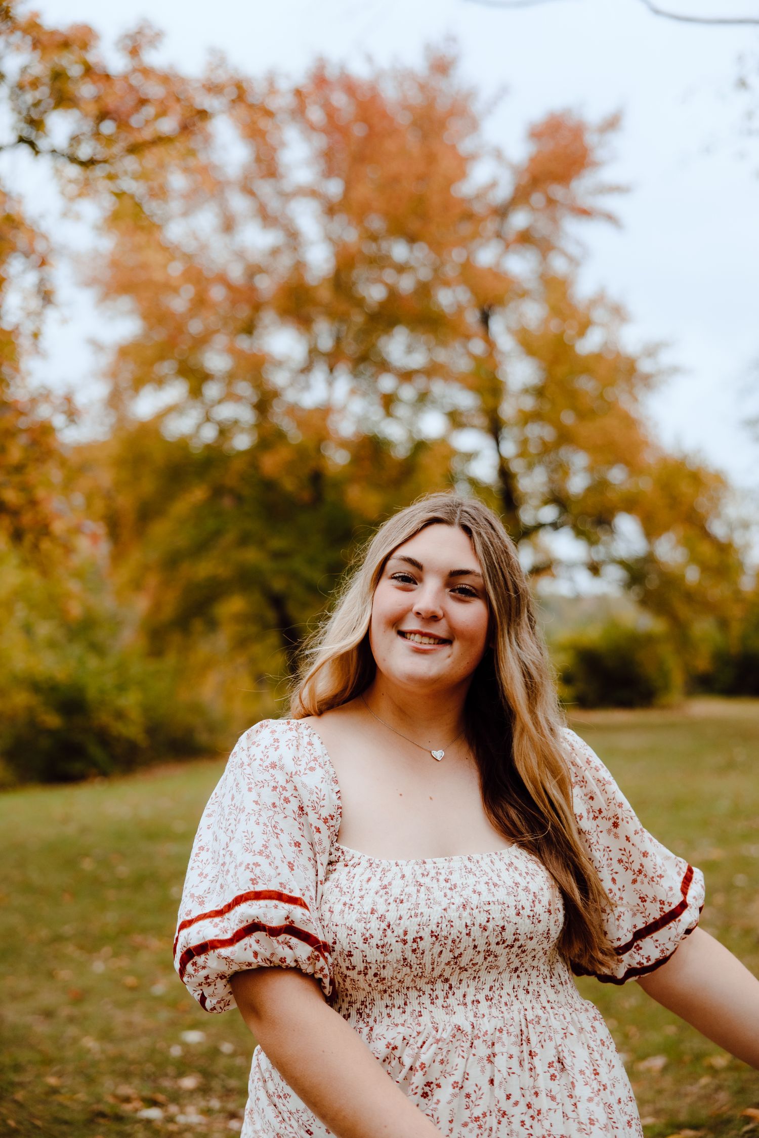 Autumn outdoor portrait in a floral dress with fall foliage in background.