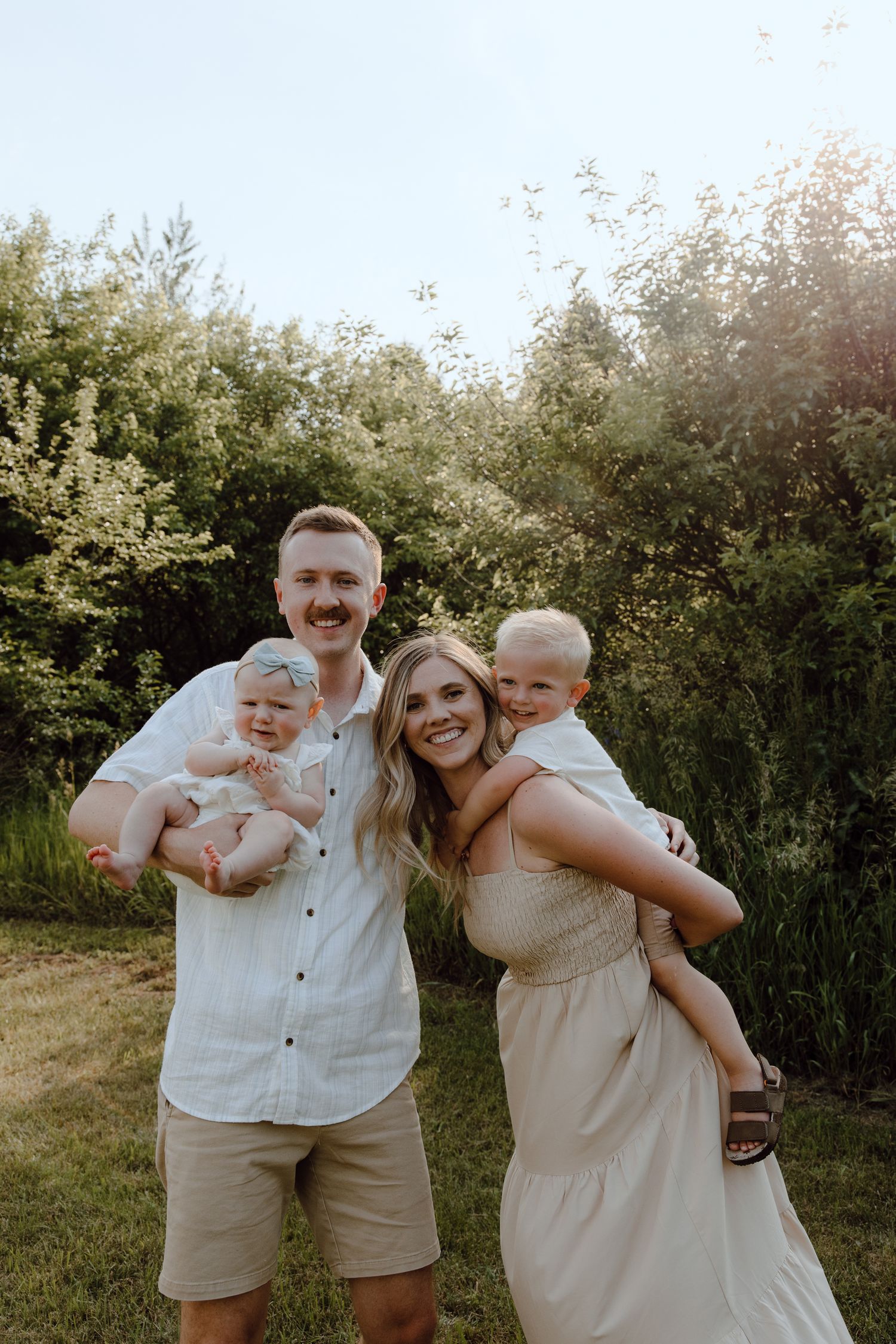 Joyful outdoor family portrait series showing parents and child laughing together against greenery.