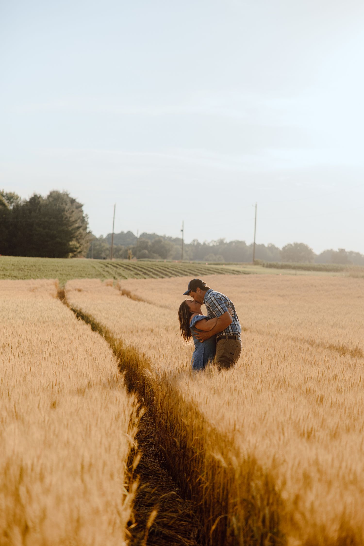 Two people share an intimate moment in a sun-drenched wheat field.