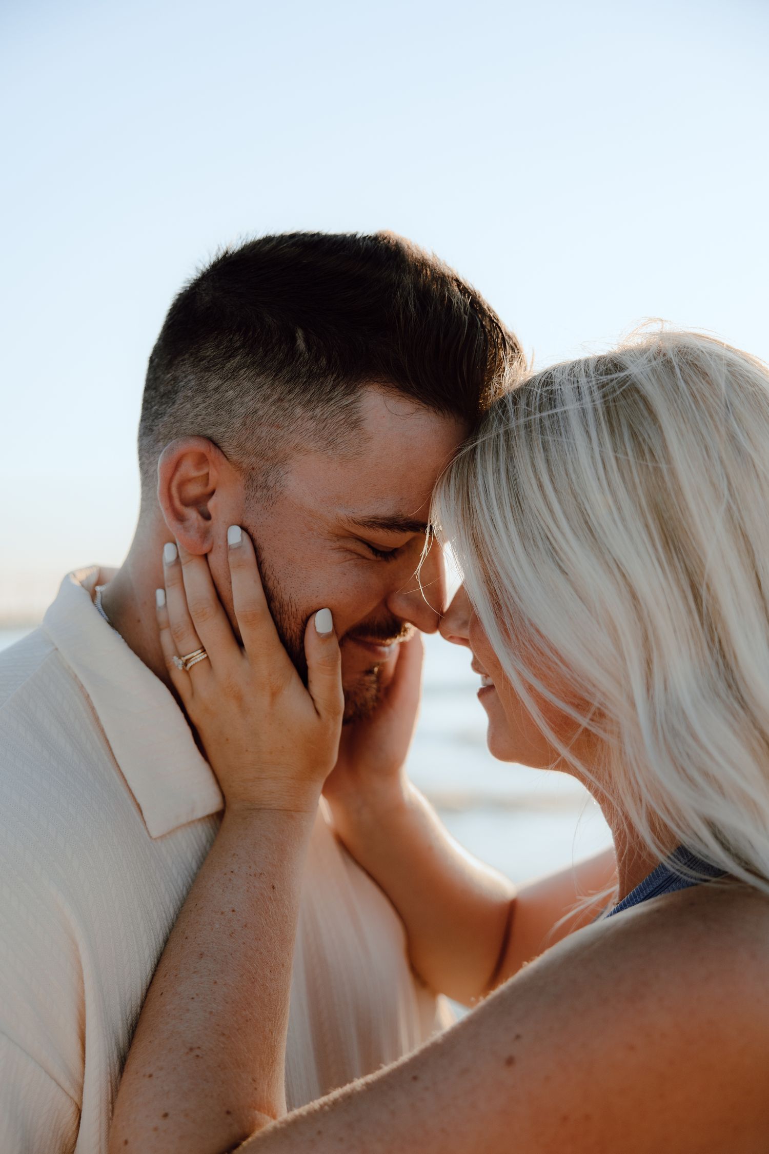 Intimate close-up of couple sharing tender moment on sunny beach.