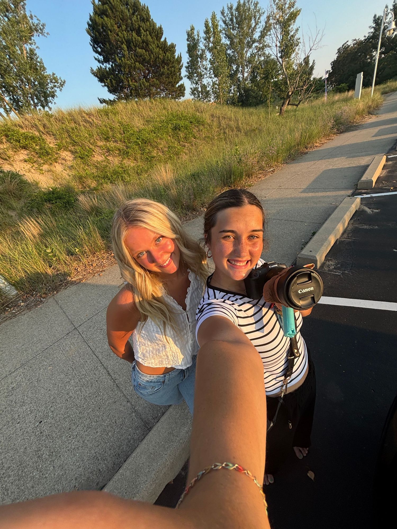 Friends taking selfies together at sunset on a hilltop path.