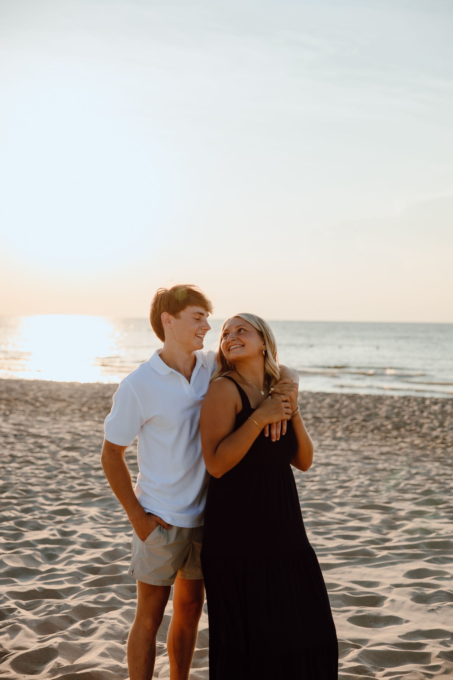 A couple shares a joyful moment together while walking on the beach at sunset.