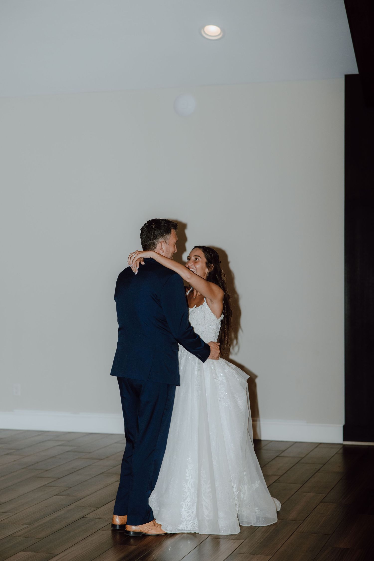 Bride and groom share their first dance in elegant ballroom on their wedding night.