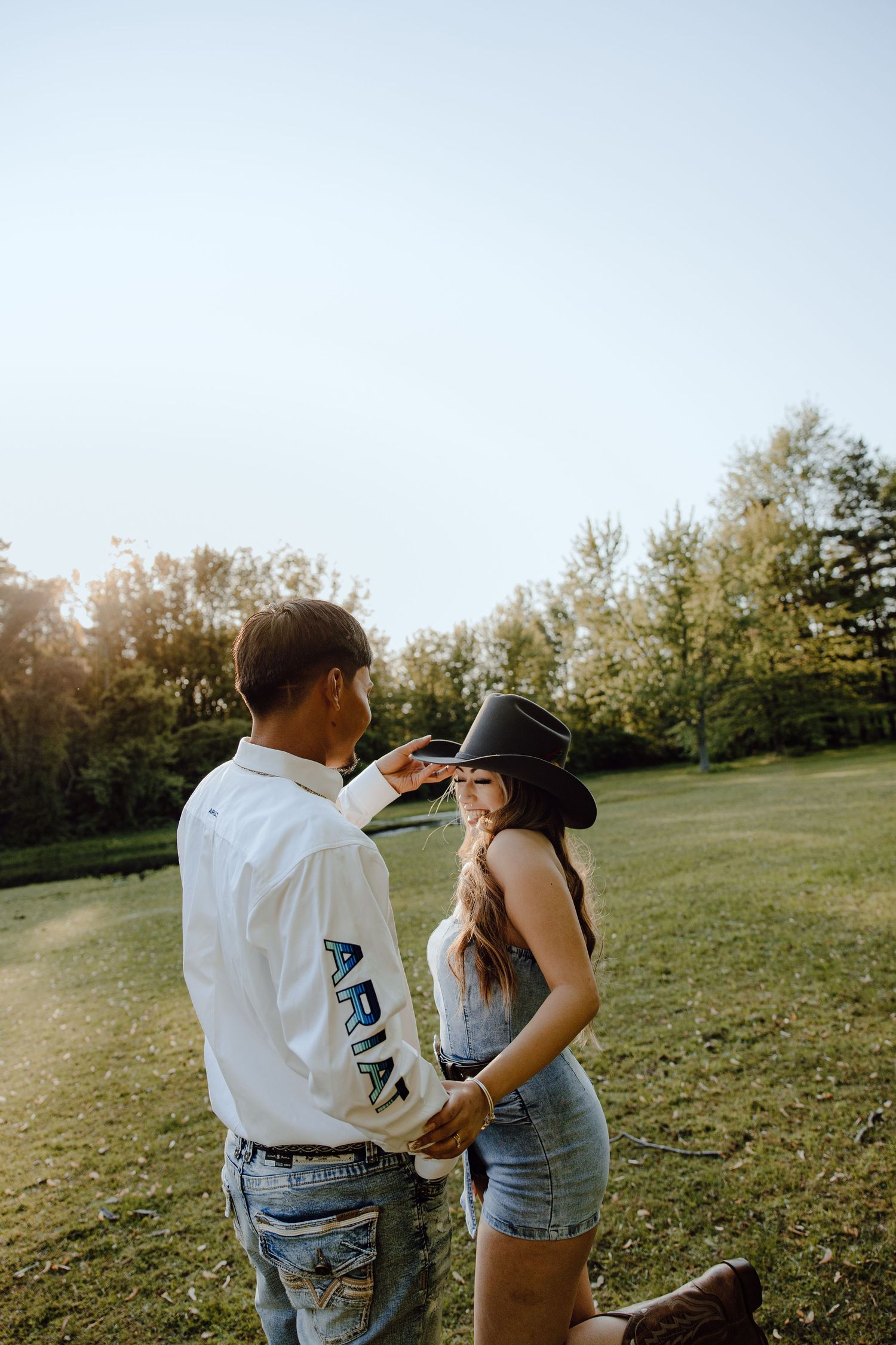 Couple in casual attire sharing an intimate moment in a sunlit field.