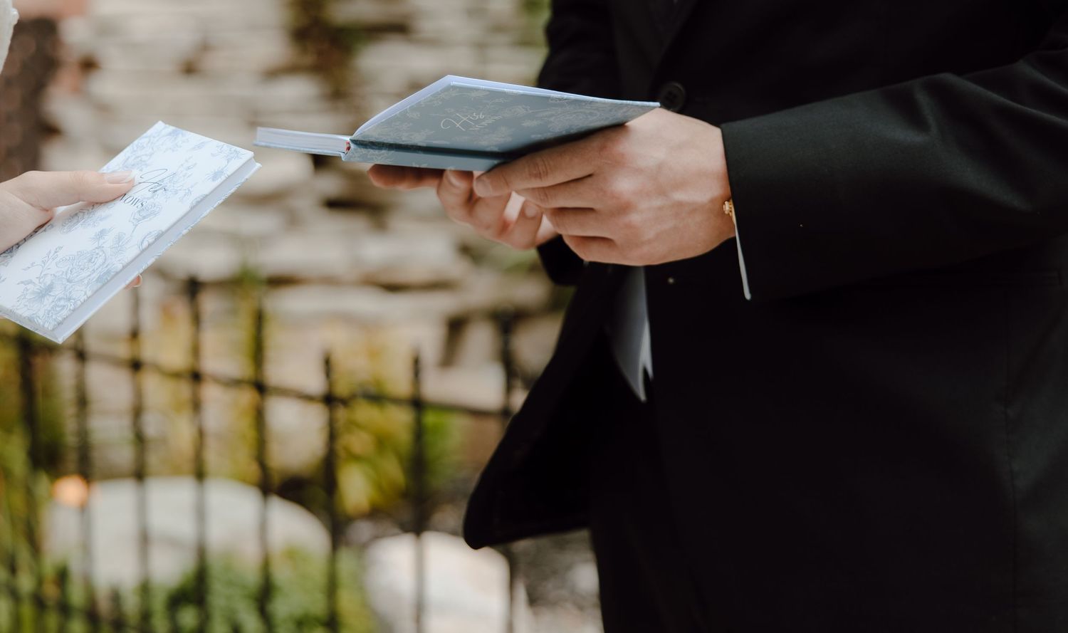A person in a black suit exchanging documents outdoors at a formal ceremony.