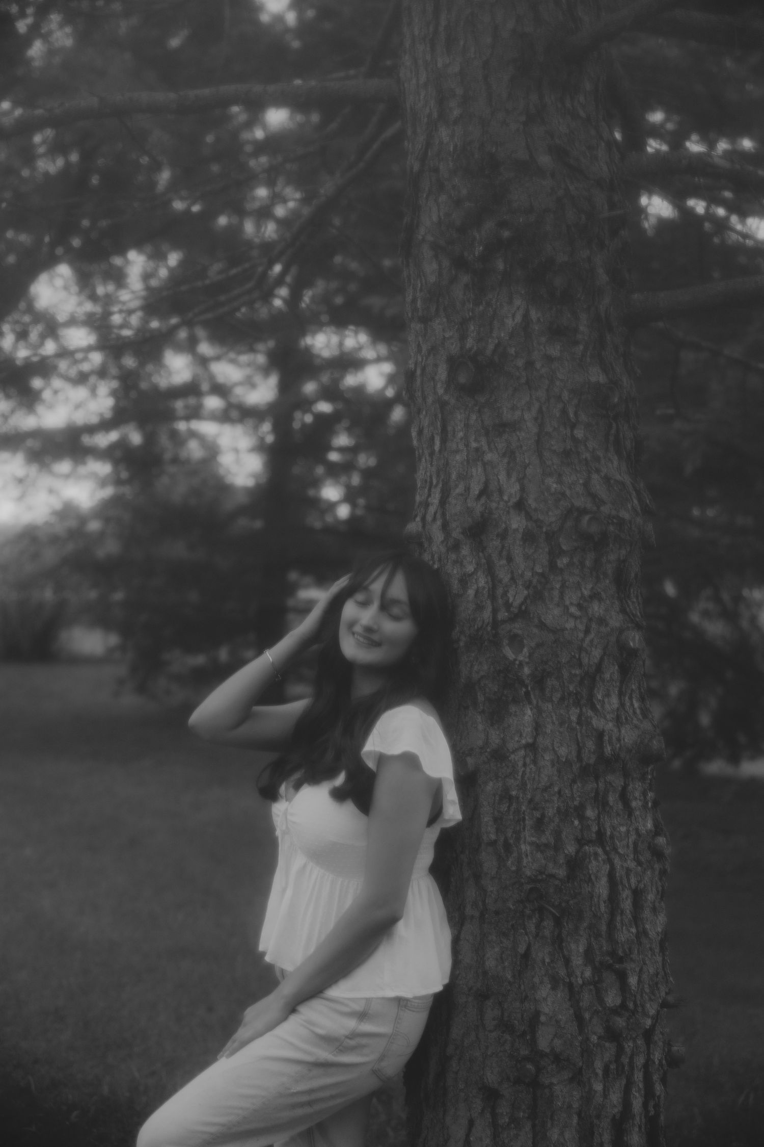 Black and white portrait session against a tree trunk in a dreamy outdoor setting.