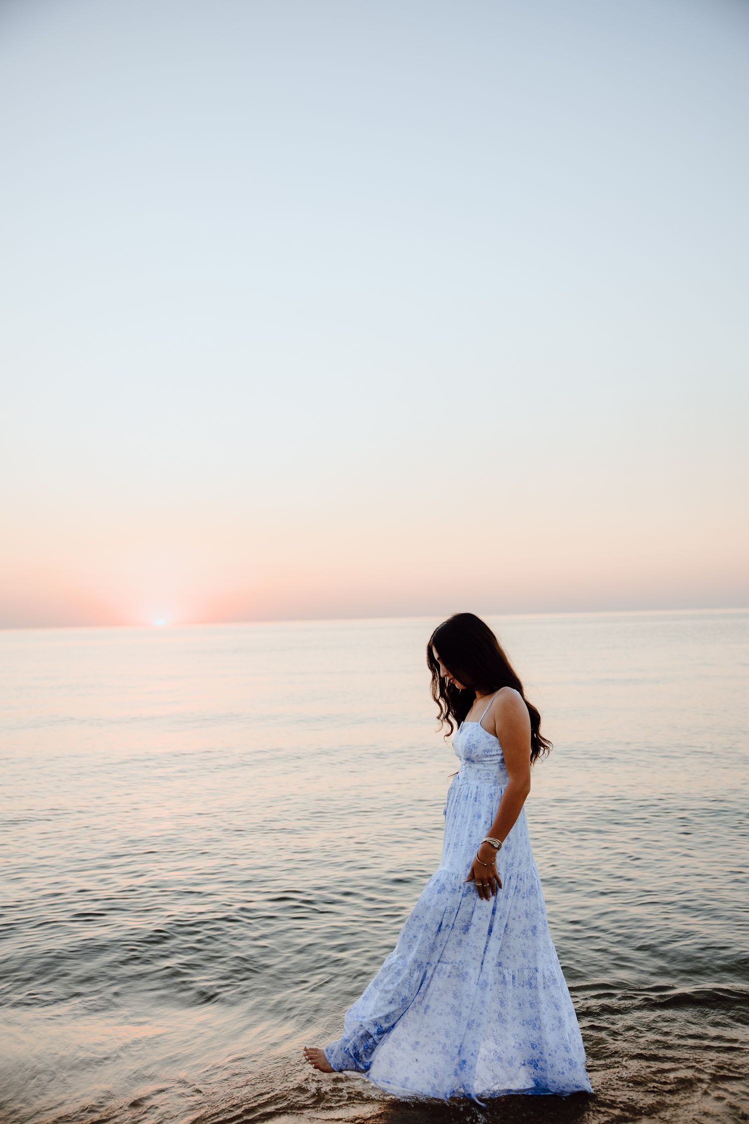 A white dress flows in the ocean breeze during golden hour at the beach.