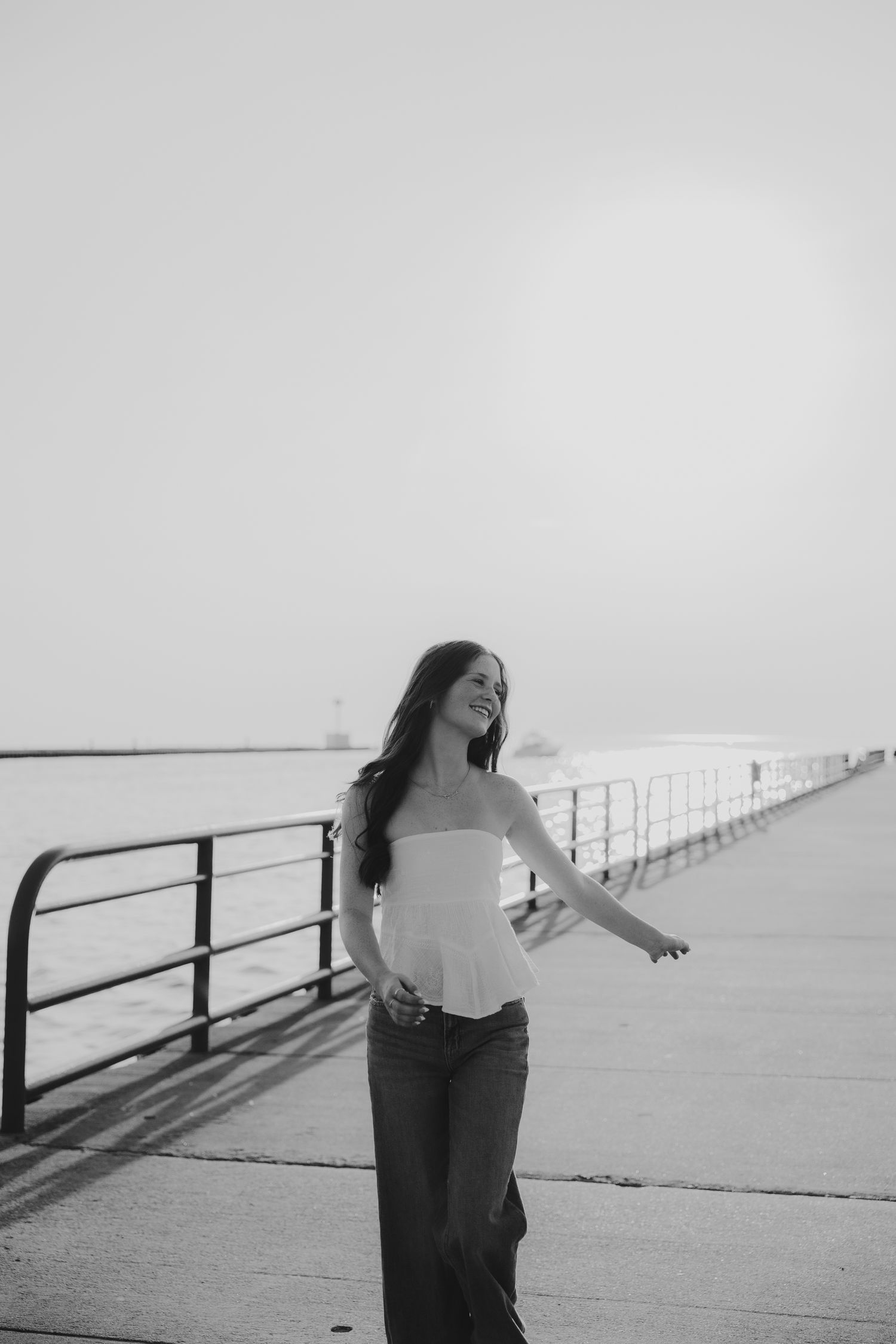 Black and white photo of someone posing by a railing on a pier.