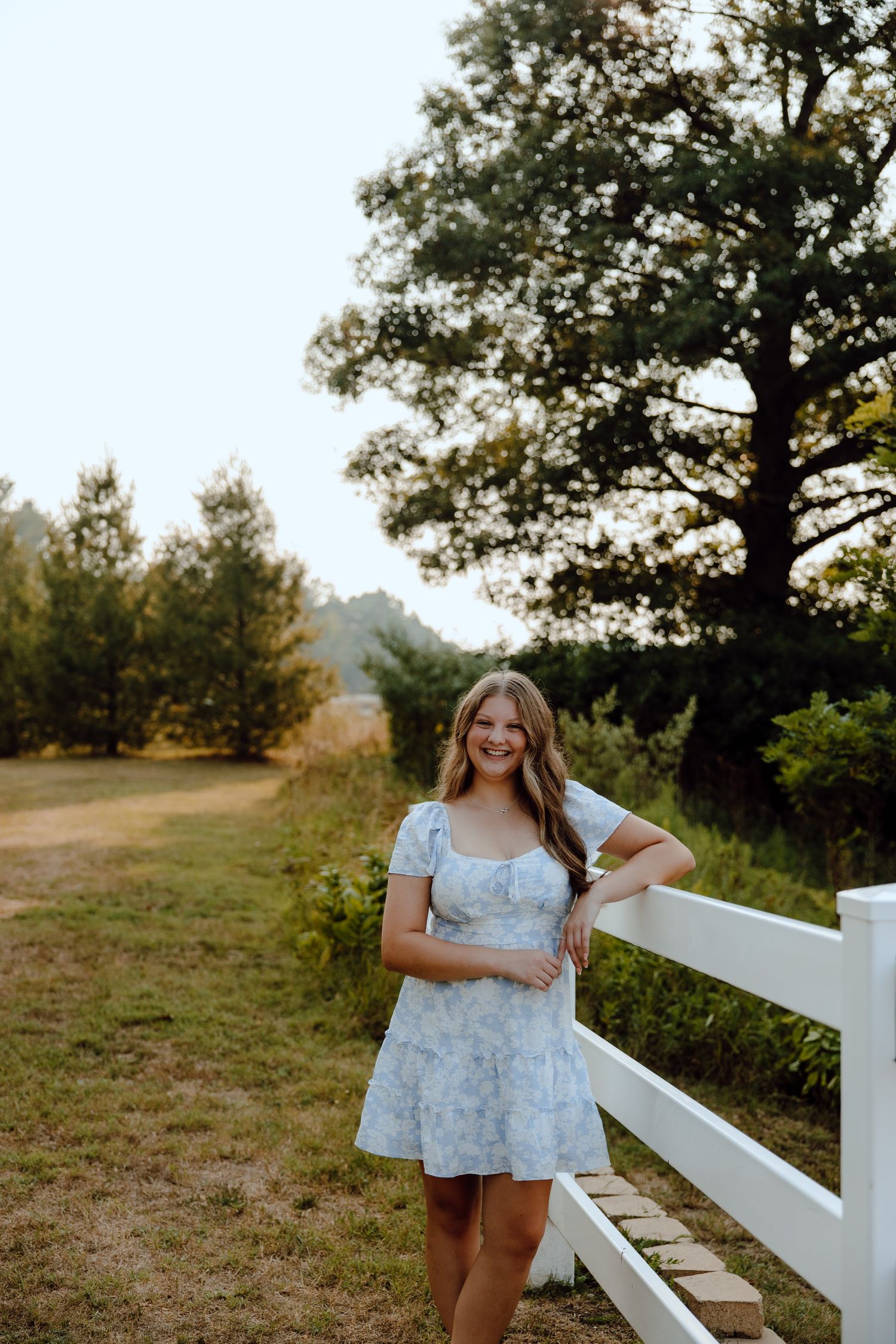 Portrait series along a white fence in a sunny outdoor setting with trees in the background.
