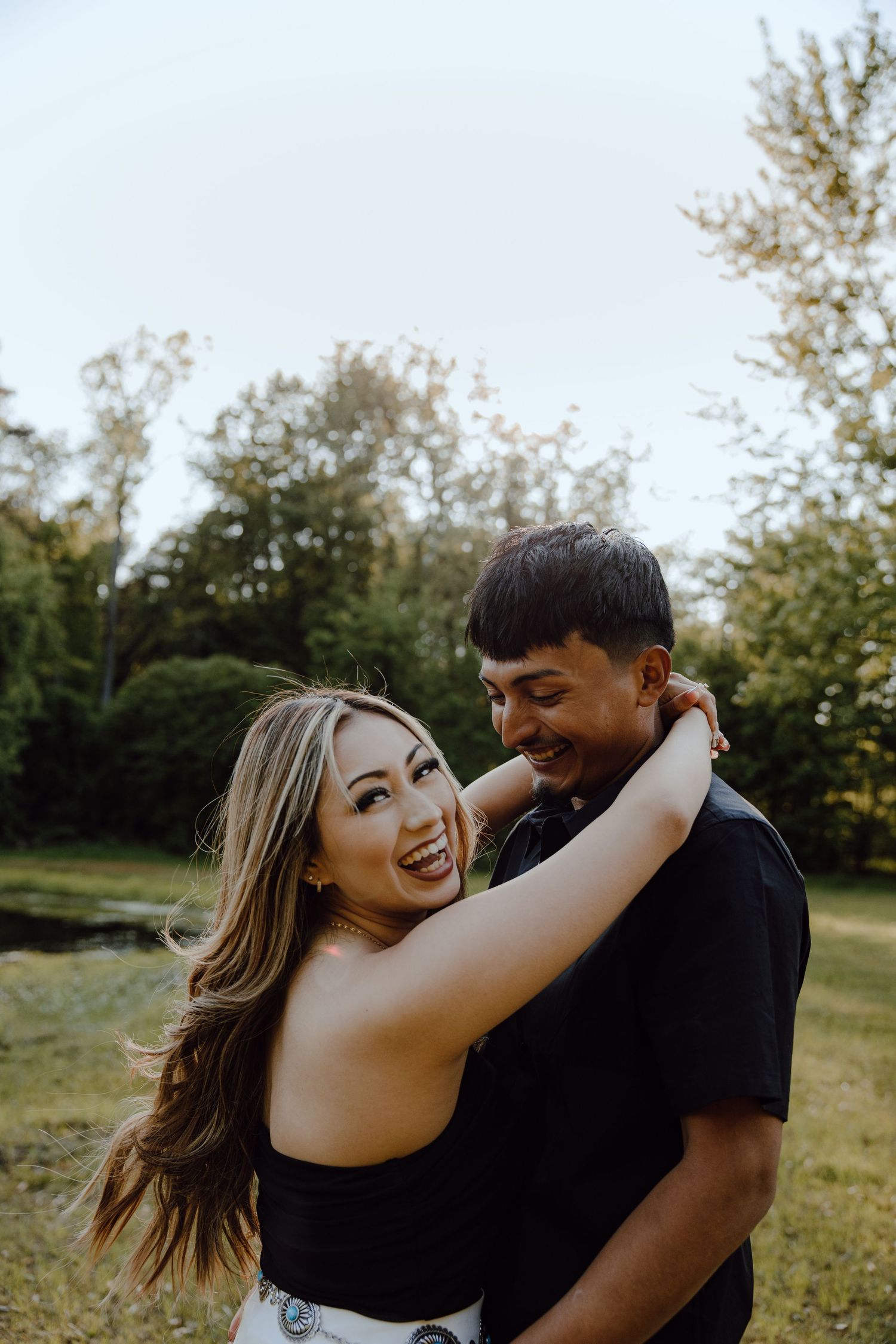Couple sharing a playful embrace outdoors against a natural backdrop.