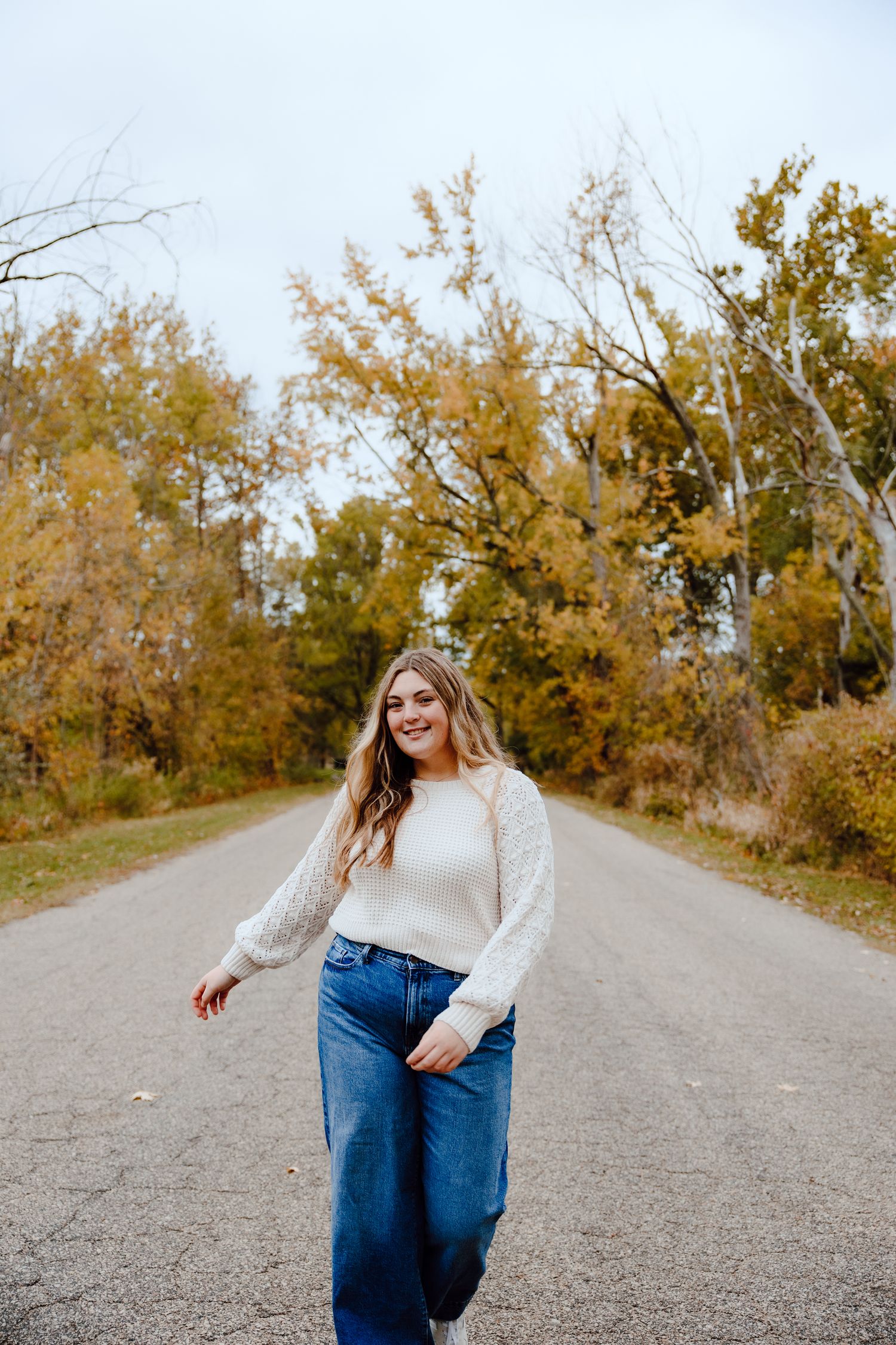 Playful poses on a gravel path with autumn trees lining the way.