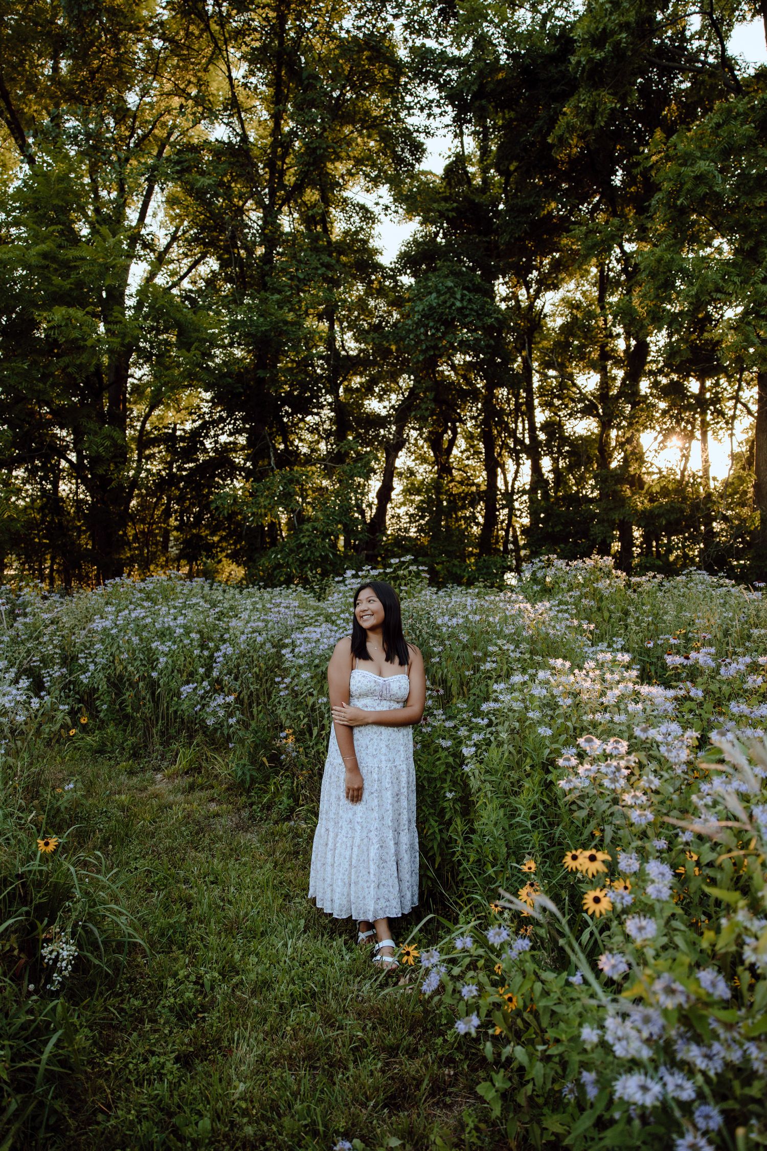 Serene portrait session in a meadow filled with white daisies and tall grass at dusk.
