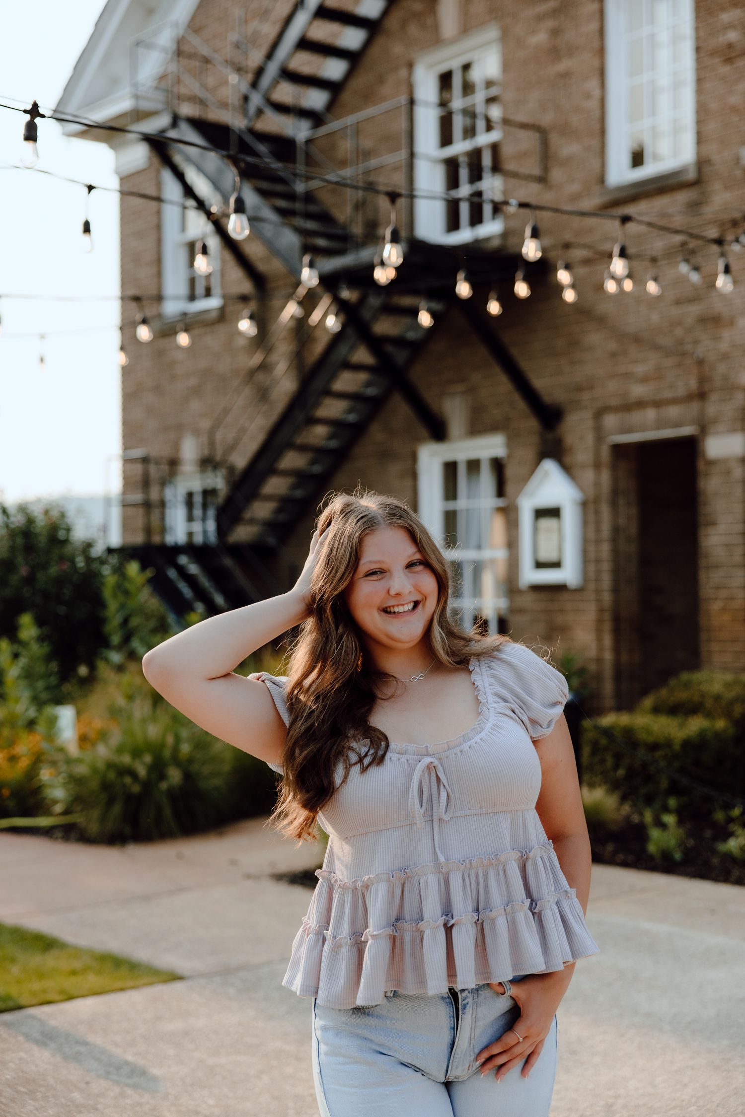 Portrait series in front of a brick building with string lights and fire escapes.