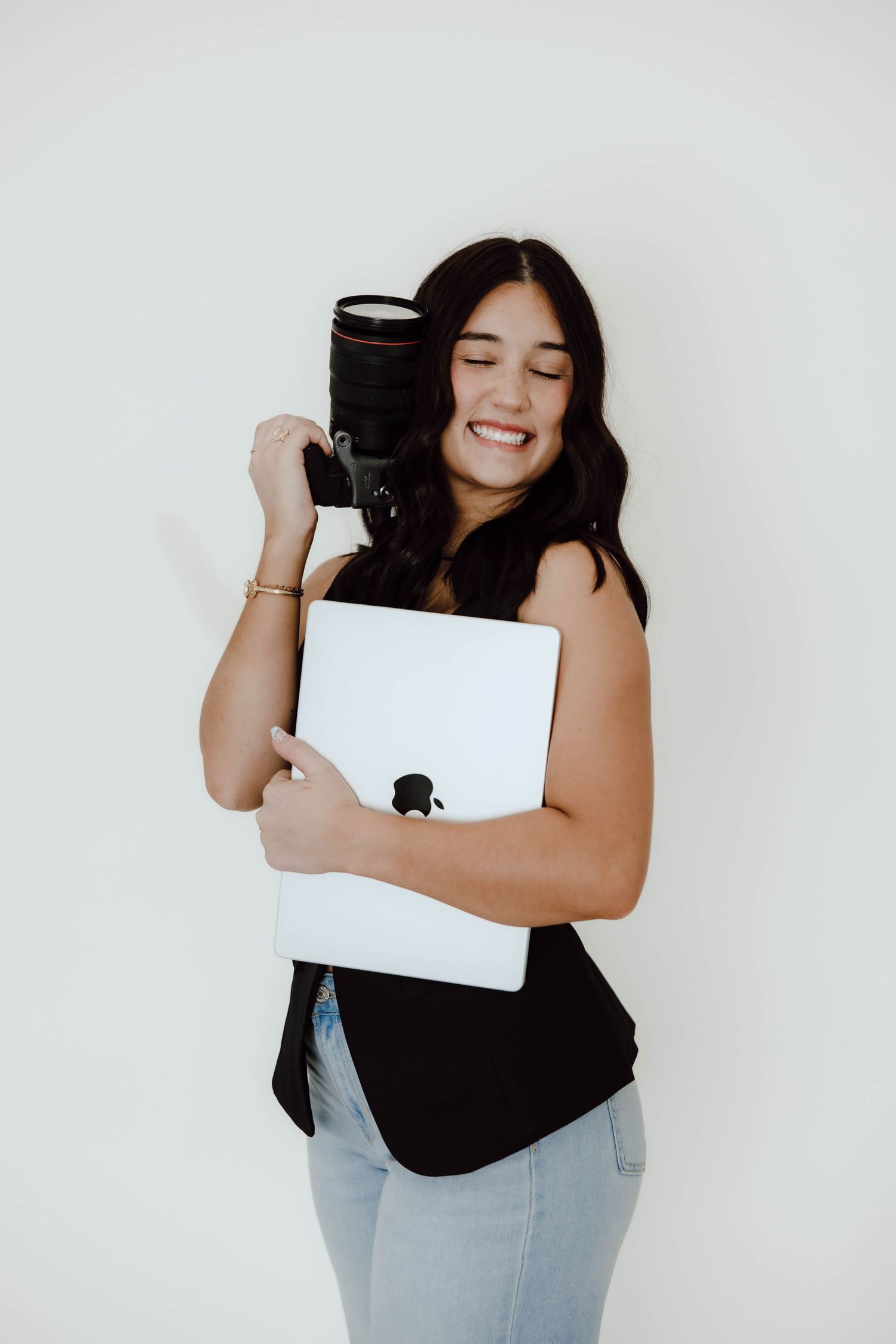 Studio portraits showing joyful expressions while holding a laptop against white background.