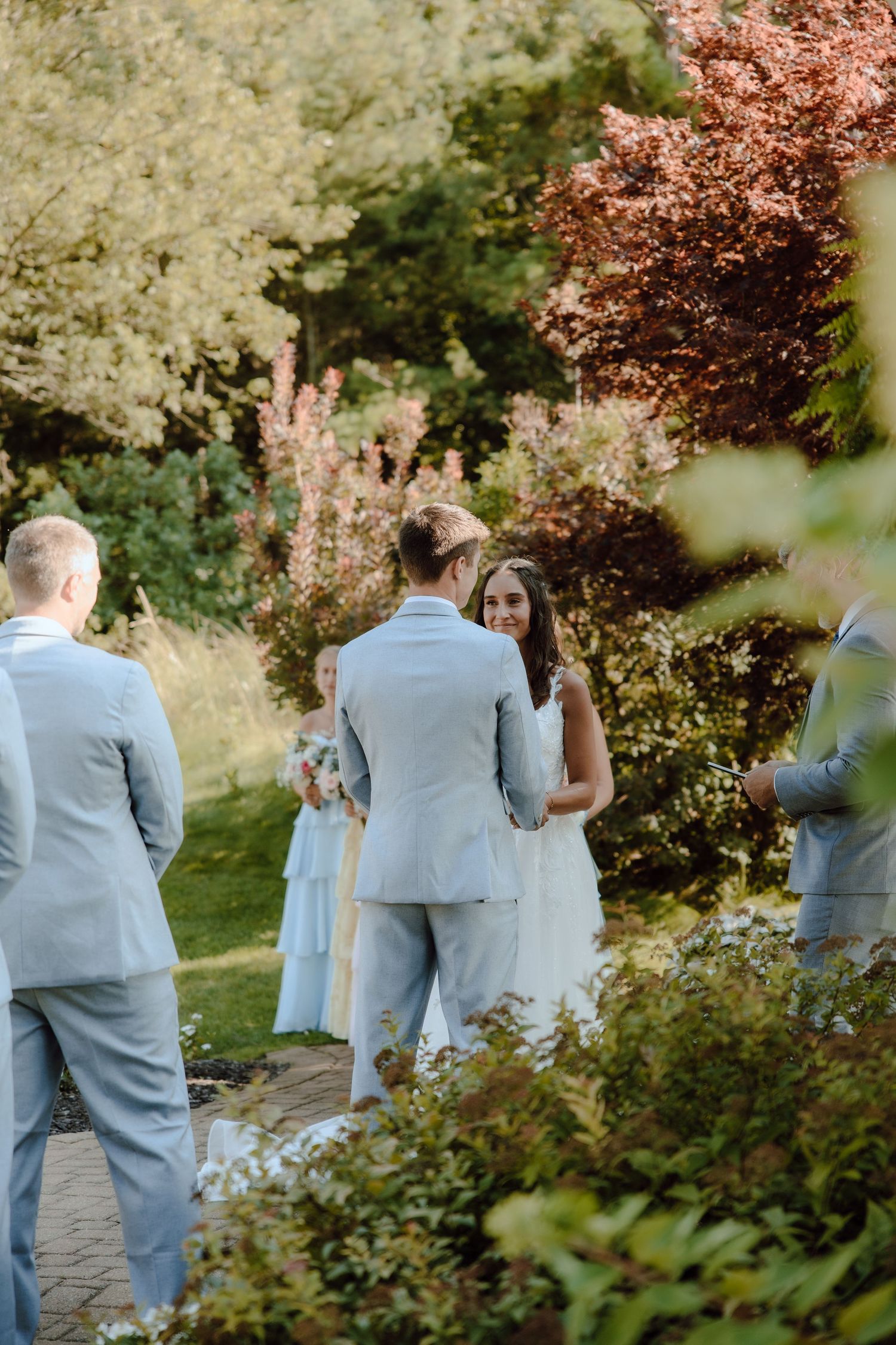Bride and groom sharing a moment during outdoor garden wedding ceremony with lush greenery.