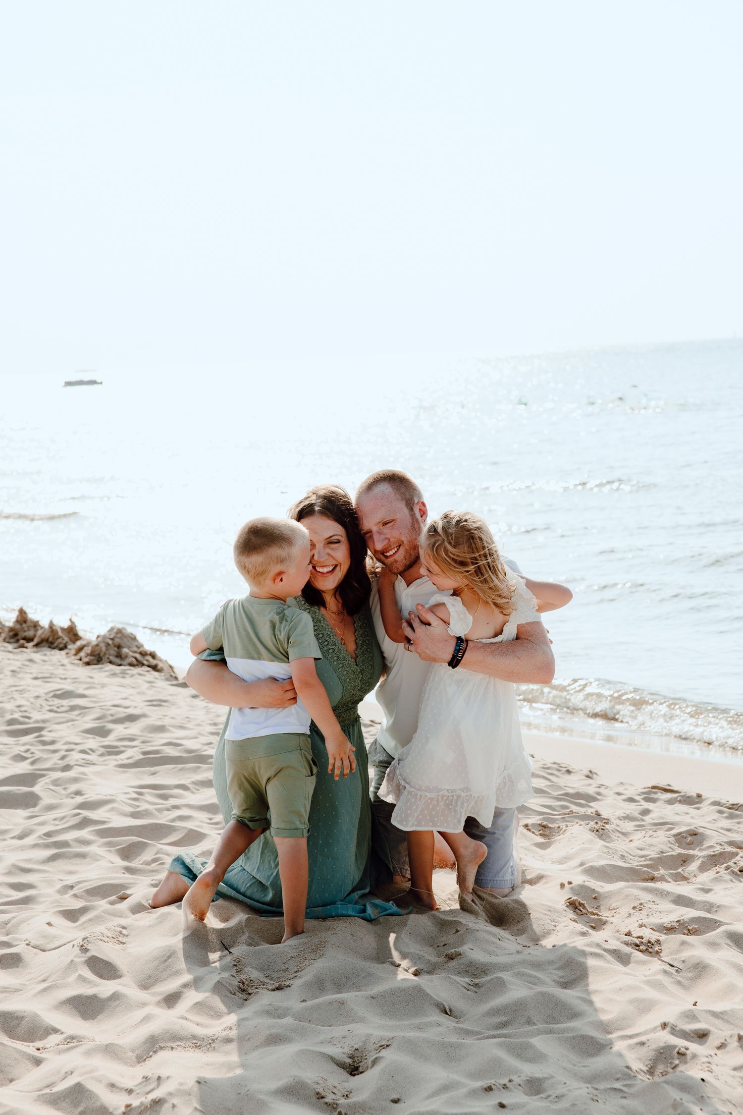 A family shares a joyful moment together while sitting on a sandy beach.