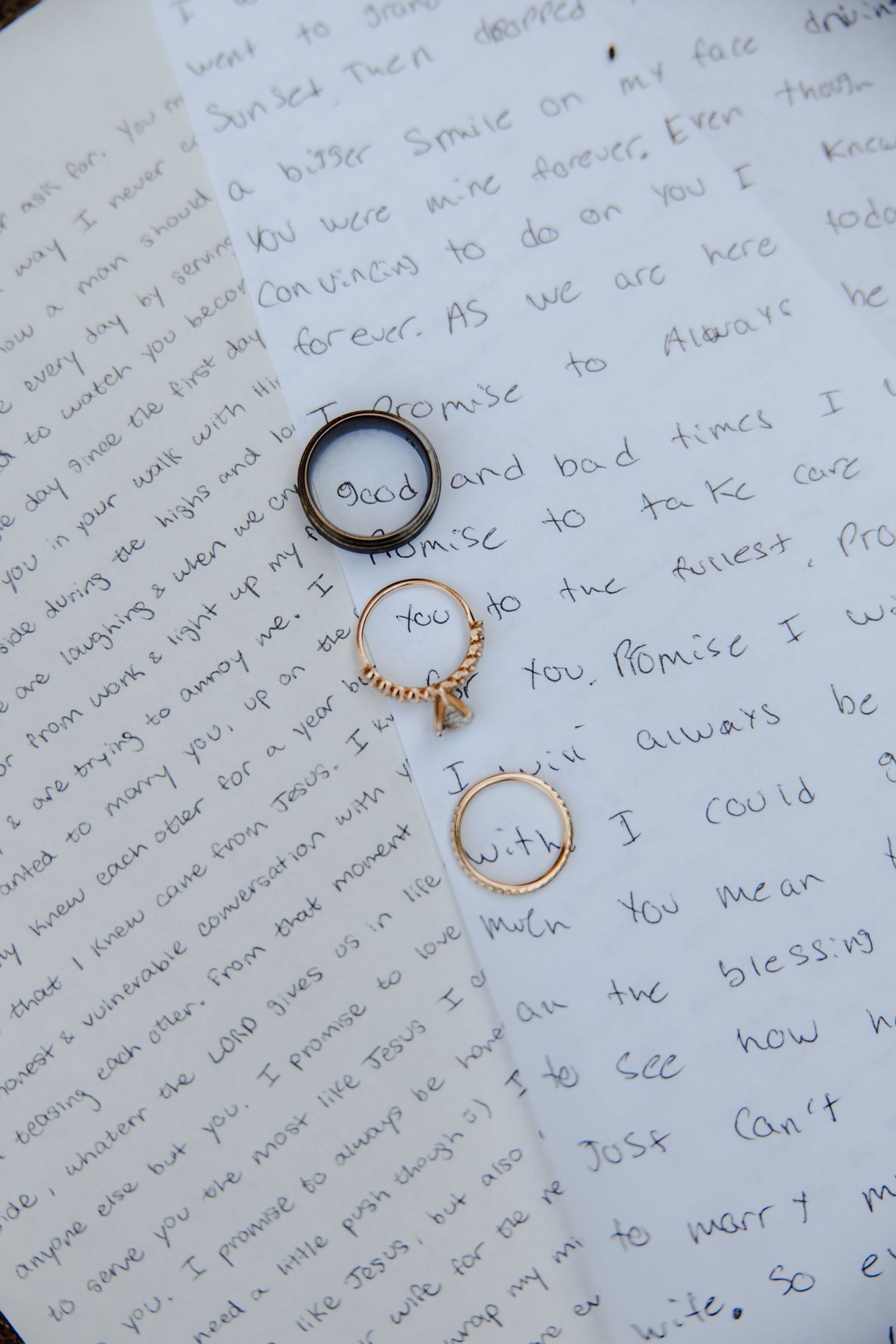 Three wedding rings resting on handwritten love letter vows, symbolizing marriage promises and commitment.