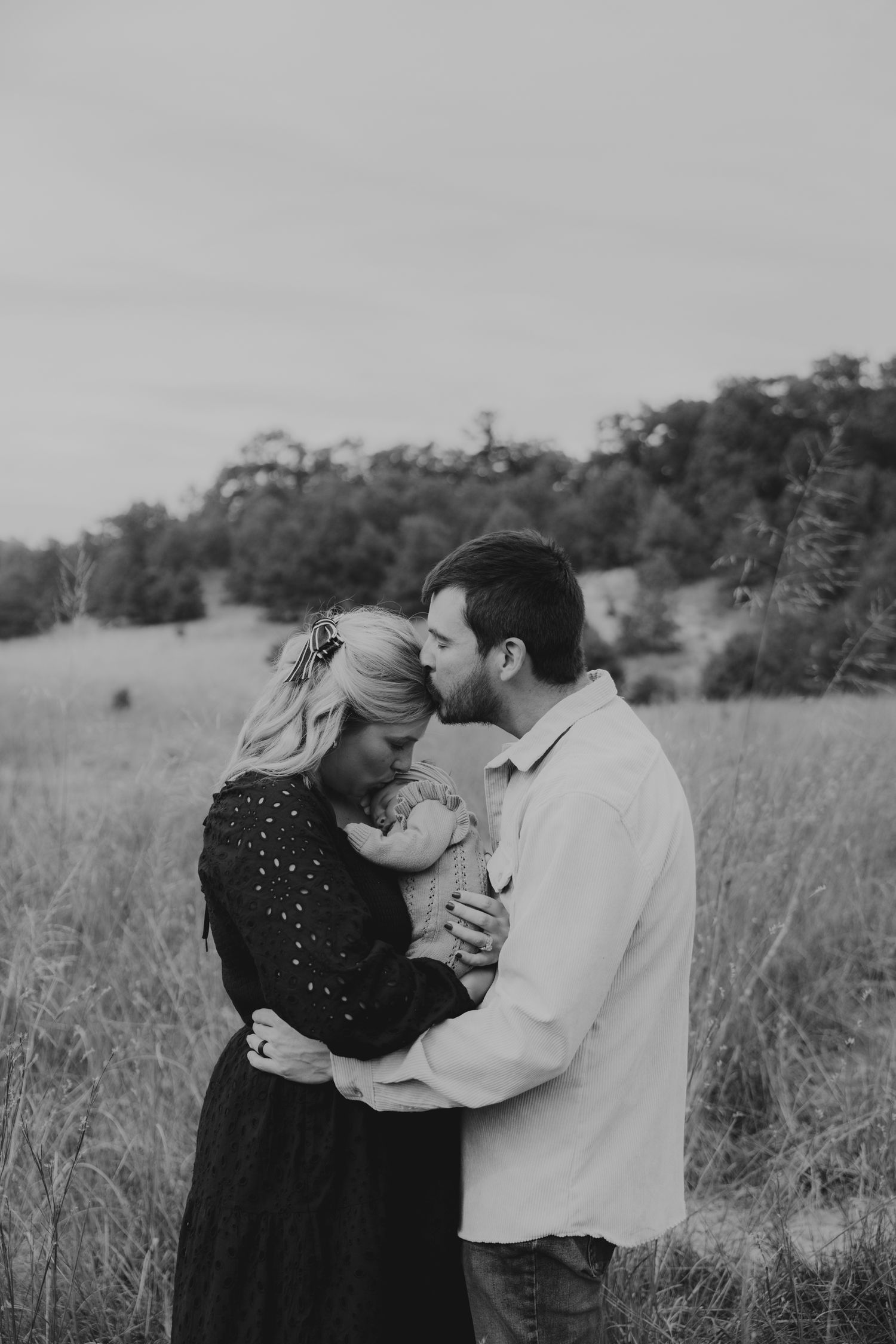 A romantic black and white photo of a couple embracing in a meadow.