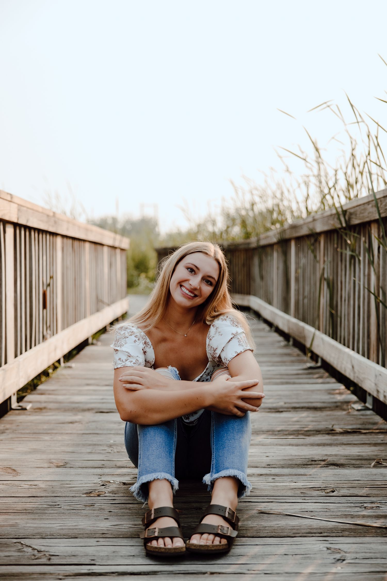 Person relaxing on wooden boardwalk during golden hour photography session.