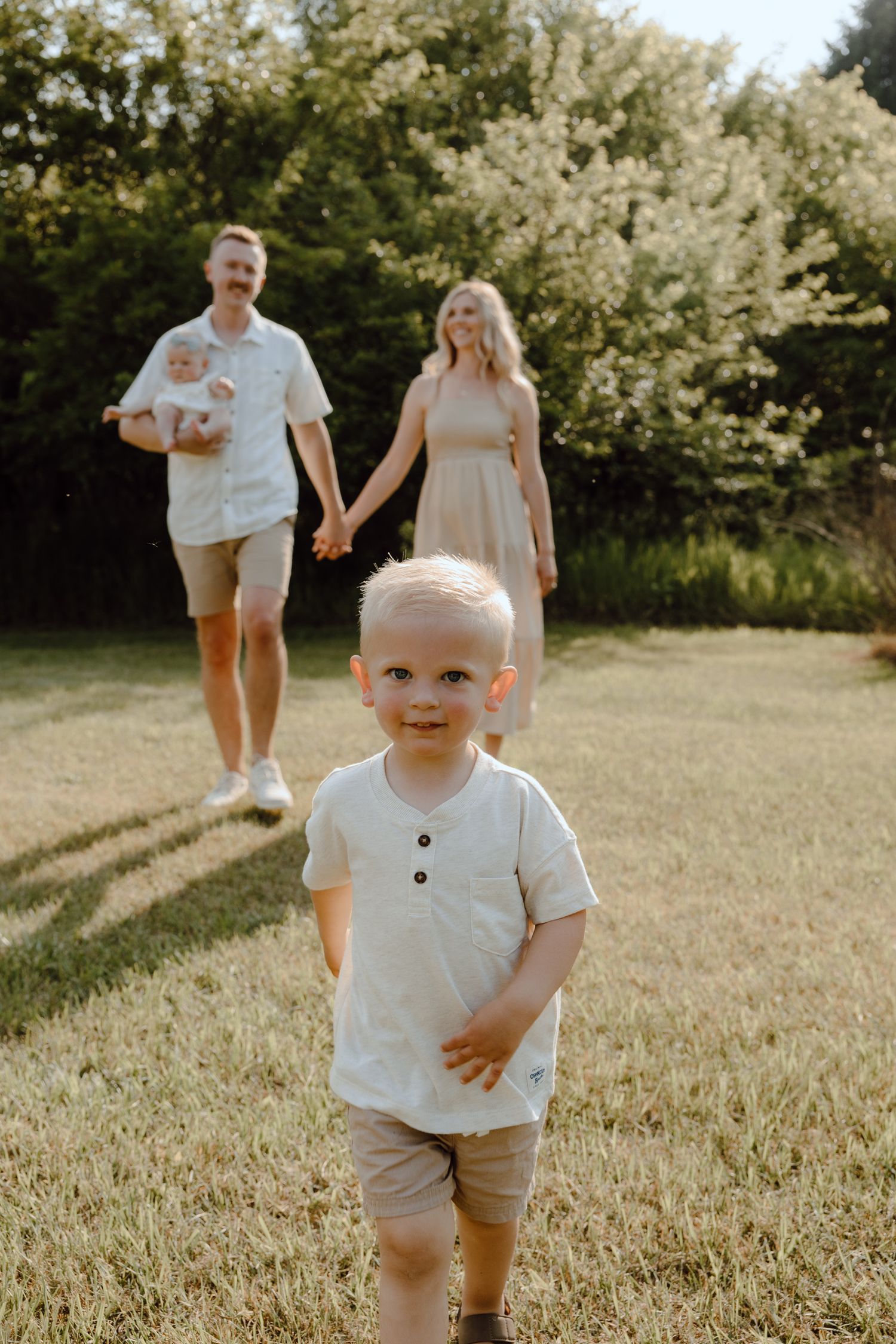 Family walking together in a sun-drenched field during golden hour.