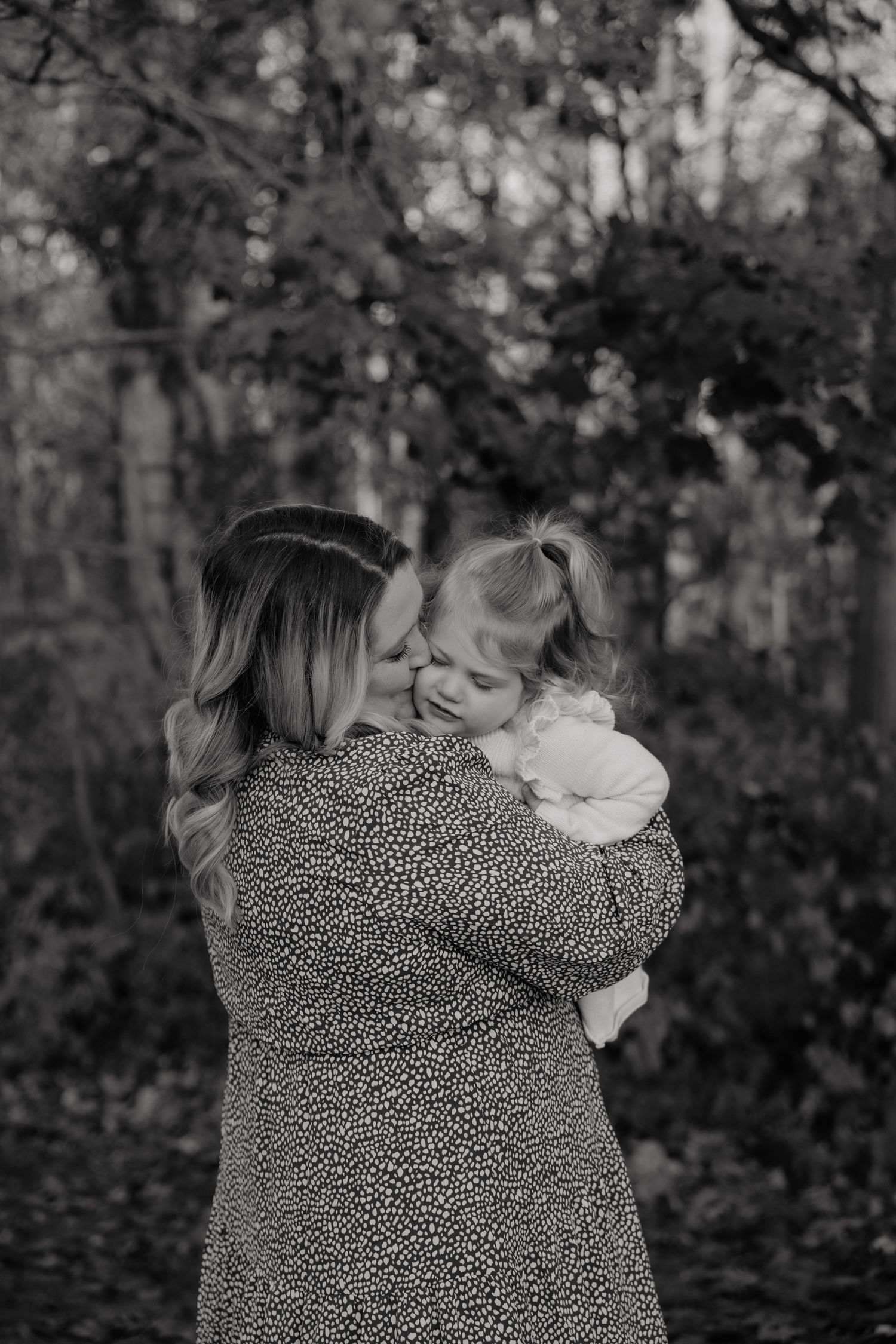 A tender black and white moment between parent and child in a forest setting.