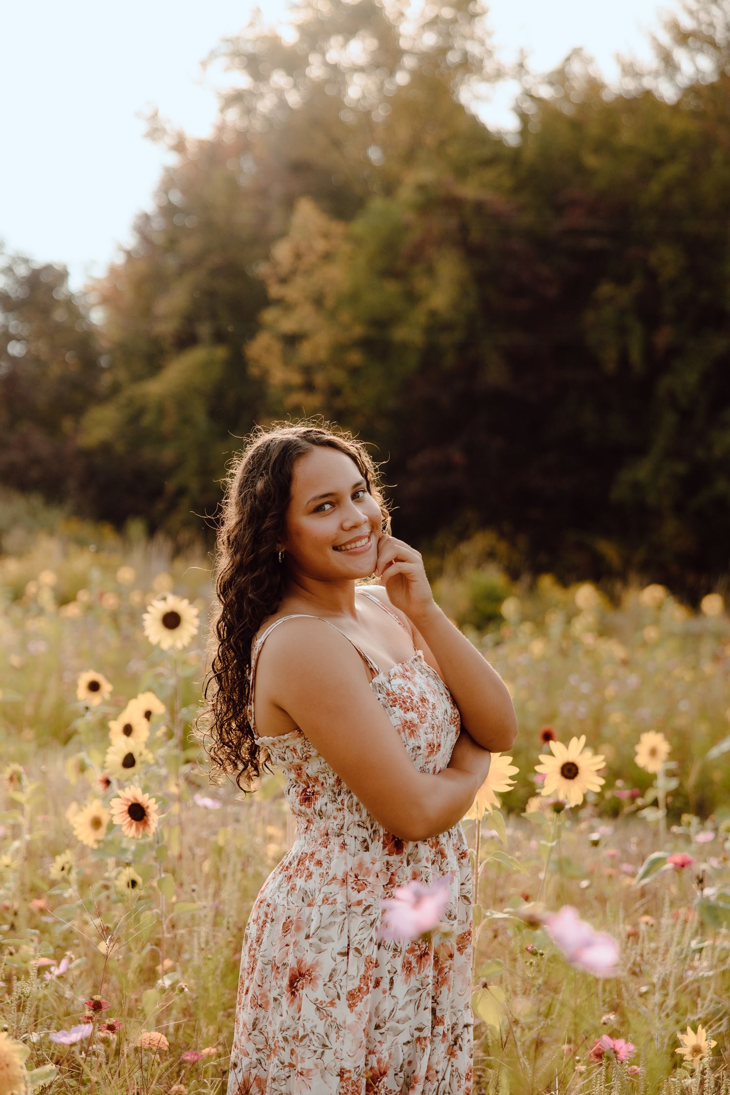 A floral dress flows gracefully through a golden meadow filled with sunflowers at sunset.