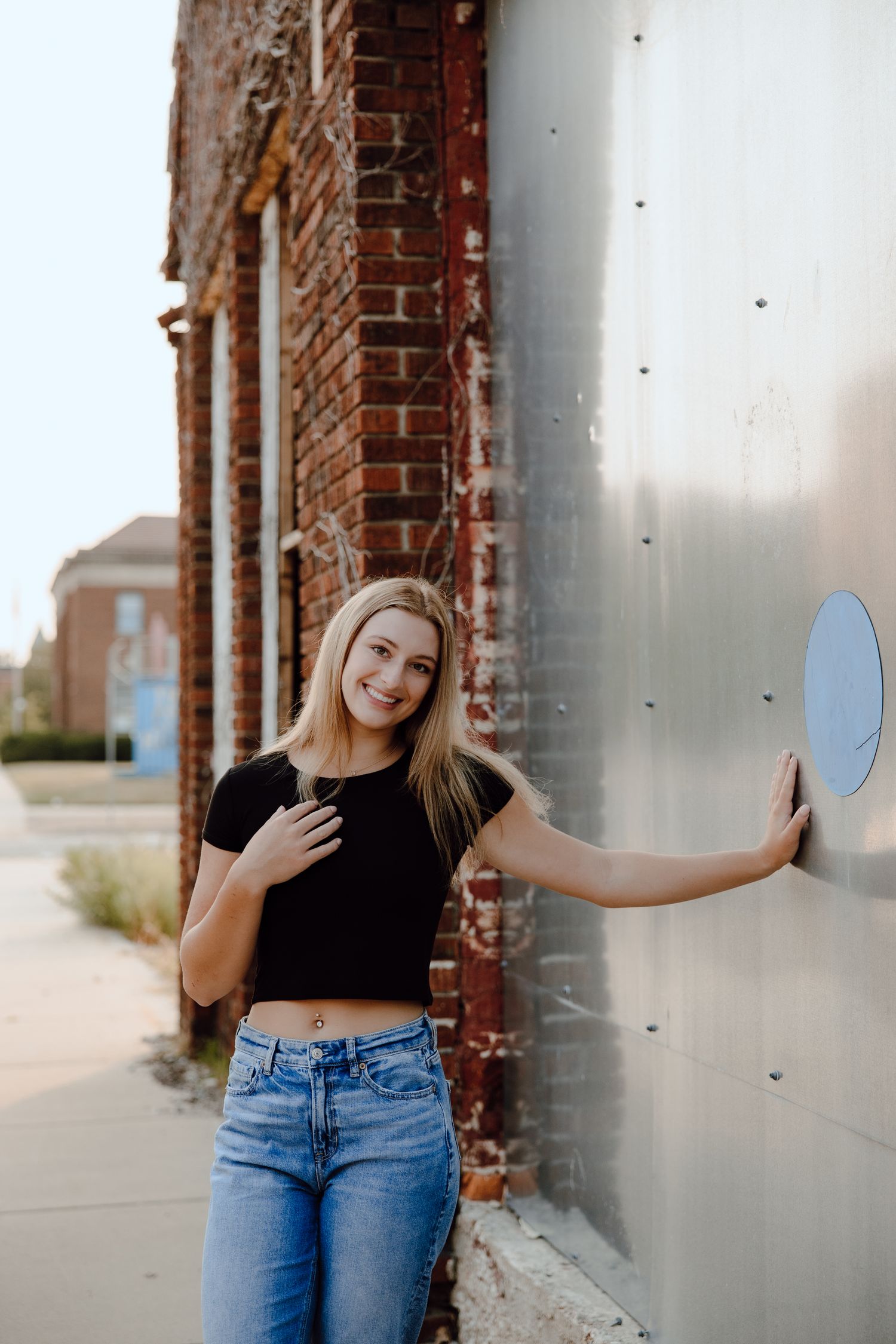 Person posing against industrial metal wall in casual outfit.