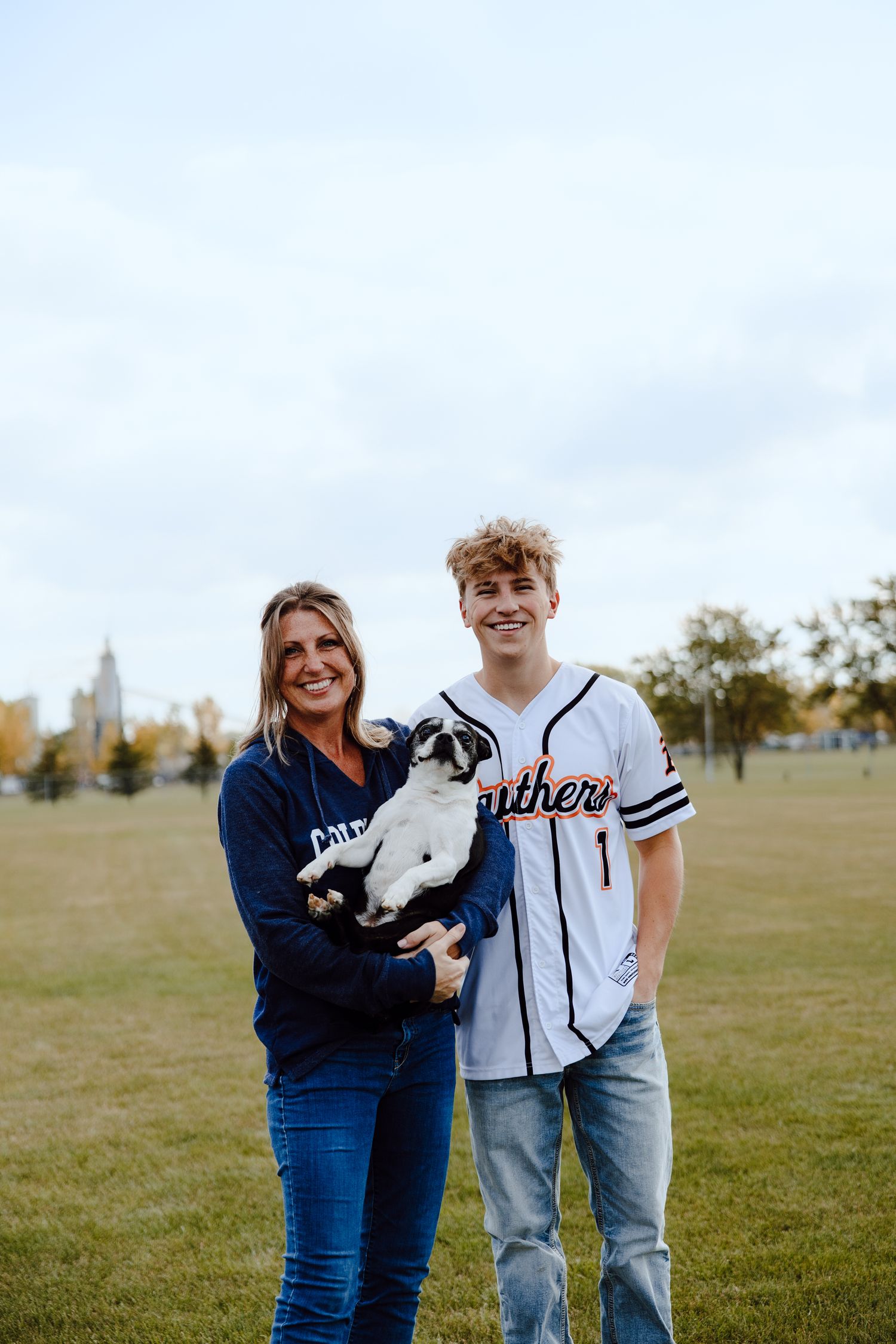 Family photo with black and white dog on baseball field.