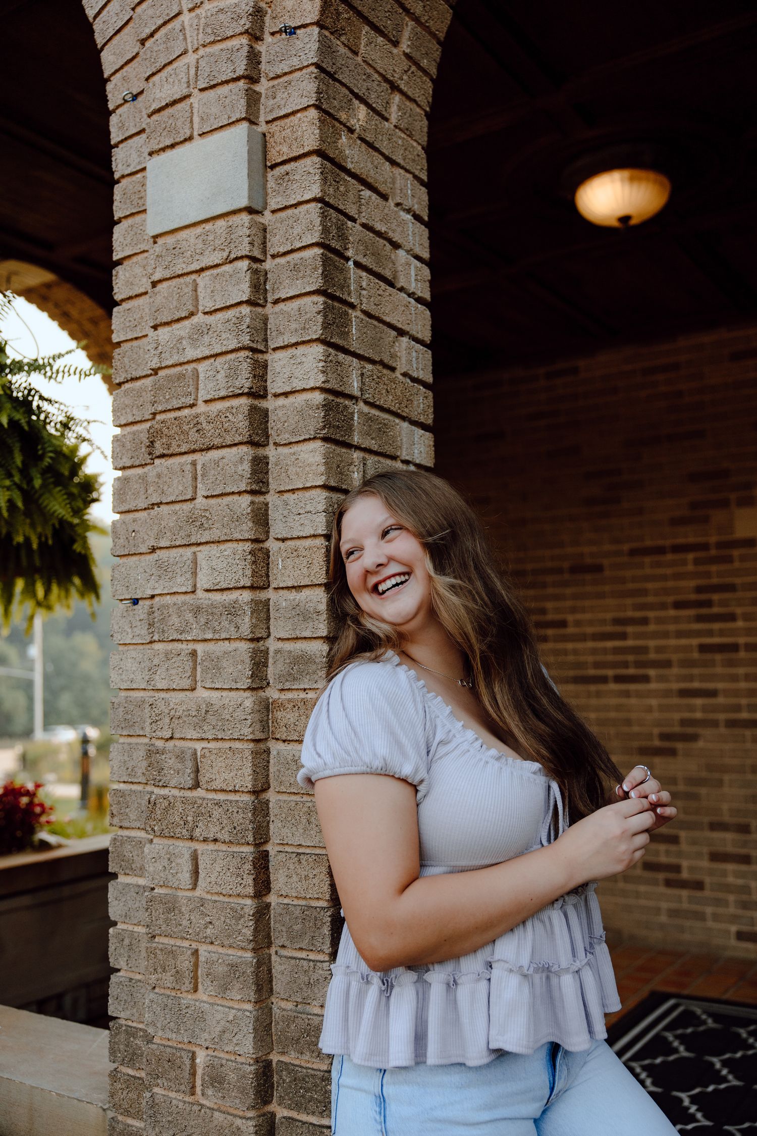 Candid portrait series against brick columns with warm lighting and architectural details.