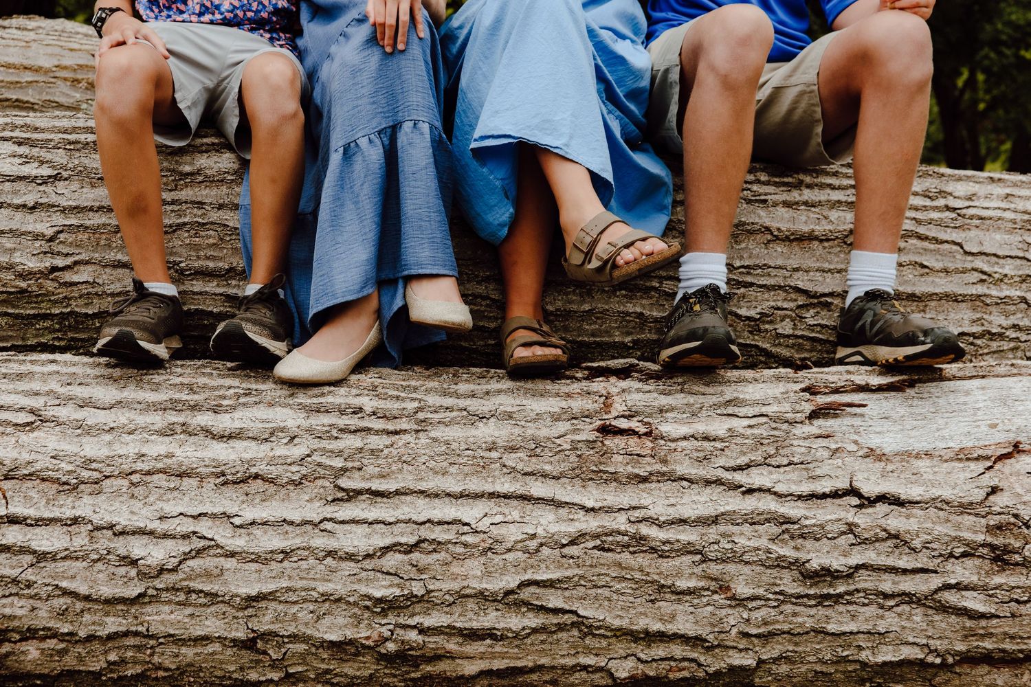Close-up view of family members' feet and legs while sitting on stone steps outdoors.